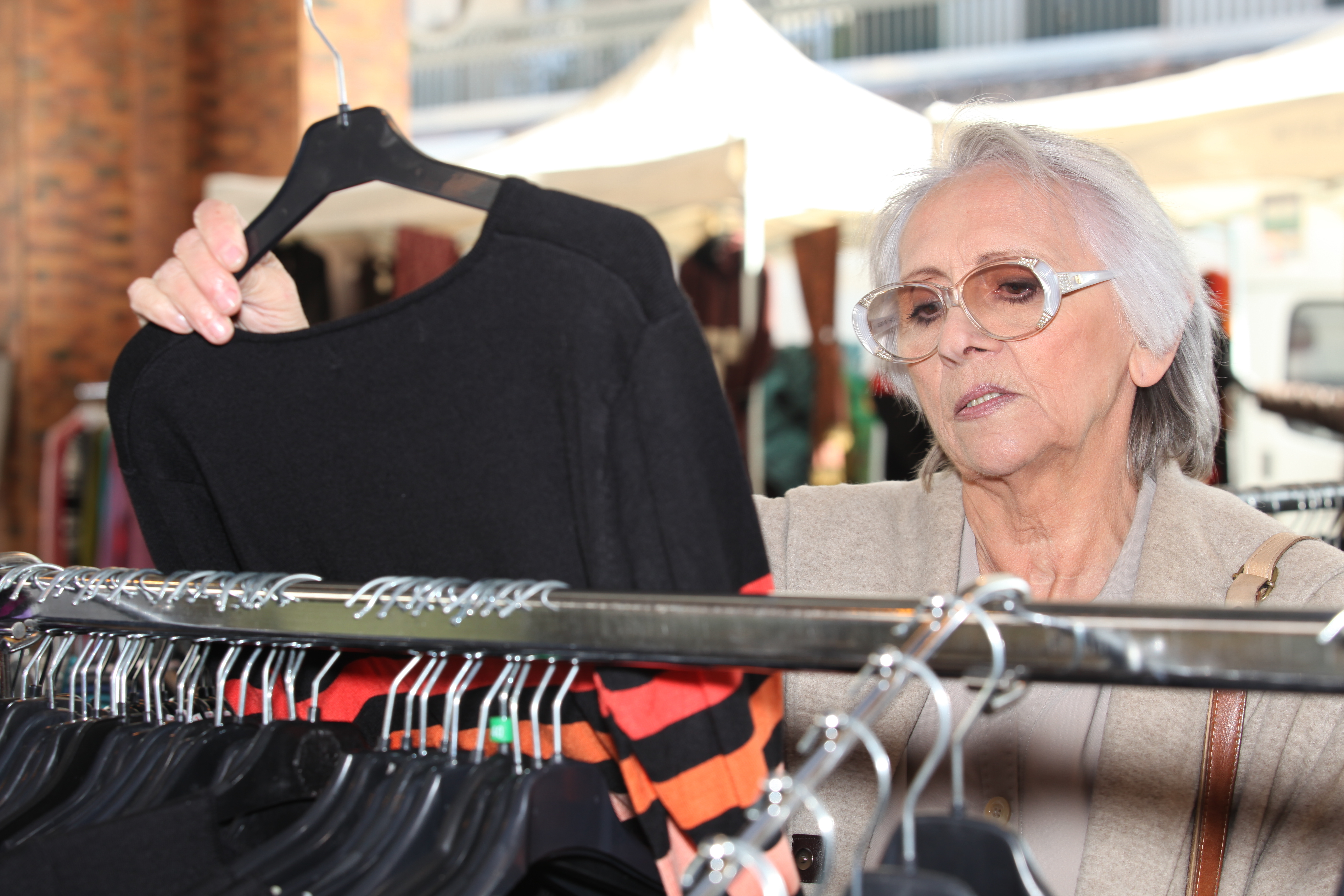Une femme plus âgée regarde la robe dans la boutique | Source : Shutterstock