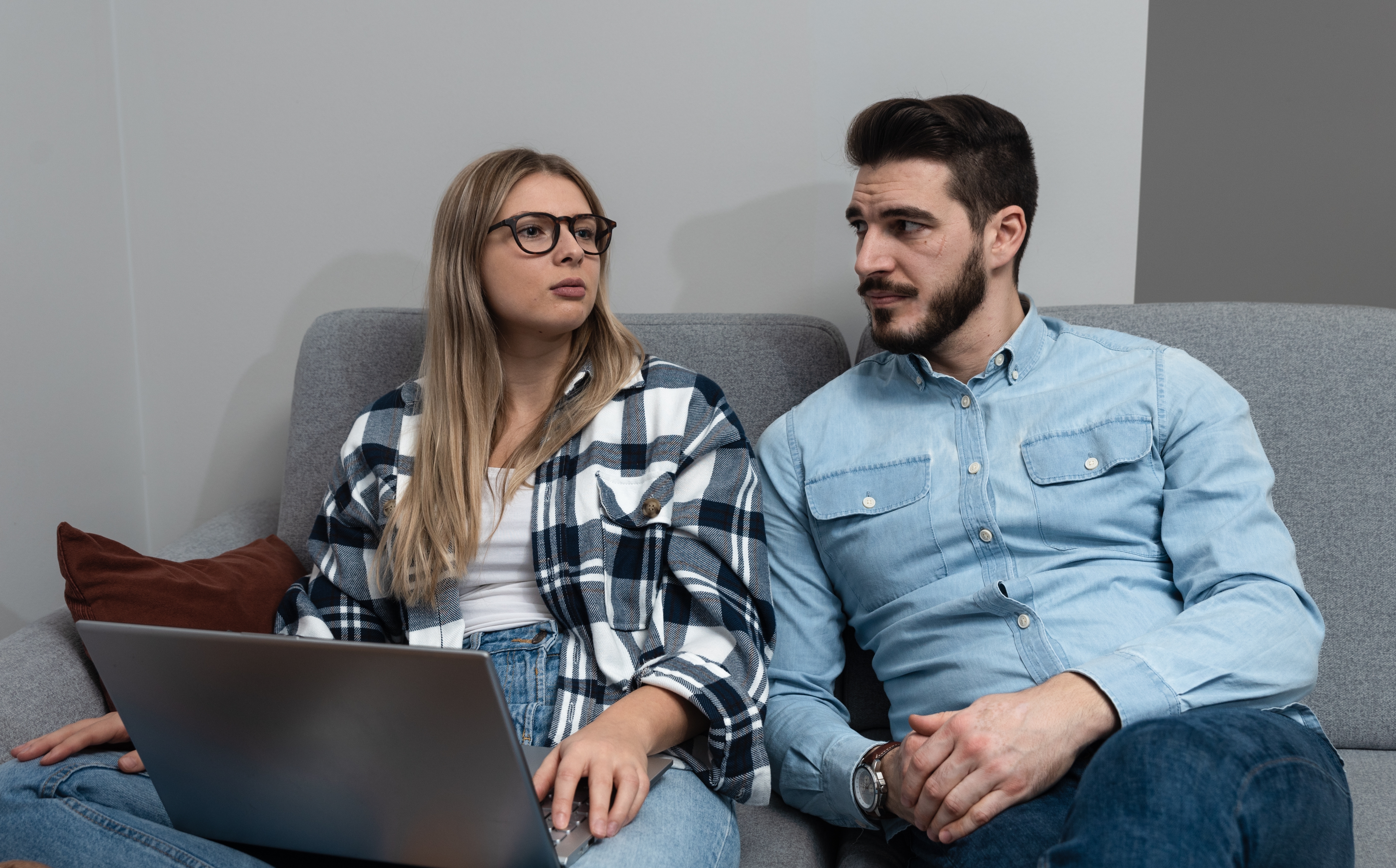 Un couple assis ensemble discutant de quelque chose tandis qu'un ordinateur portable est posé sur les genoux de la femme | Source : Shutterstock