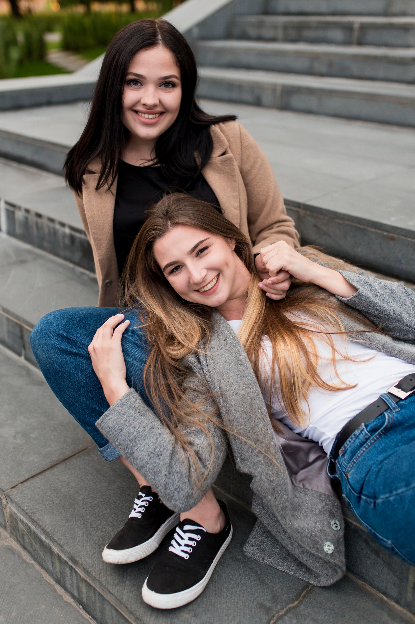 Deux jeunes femmes heureuses se lient d'amitié à l'extérieur sur des escaliers | Source : Freepik