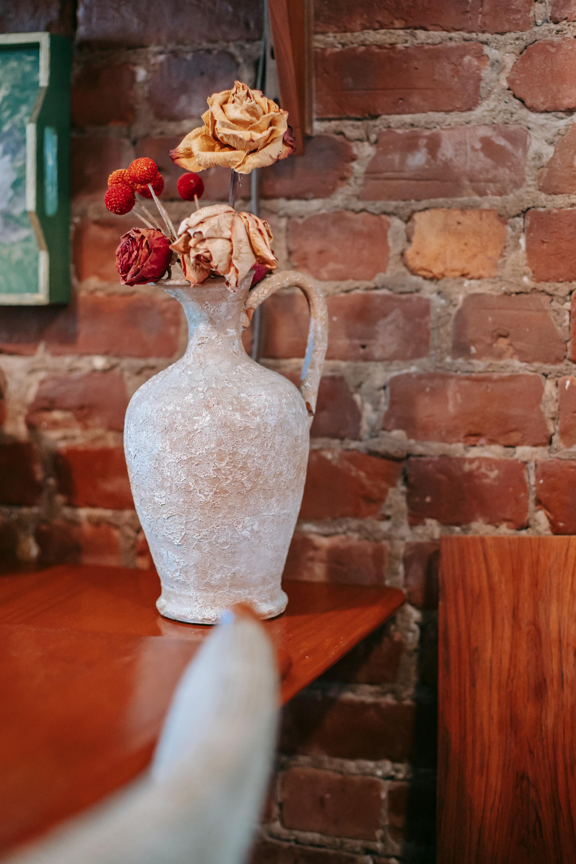 Un vase contenant des roses séchées posé sur une table en bois | Source : Pexels
