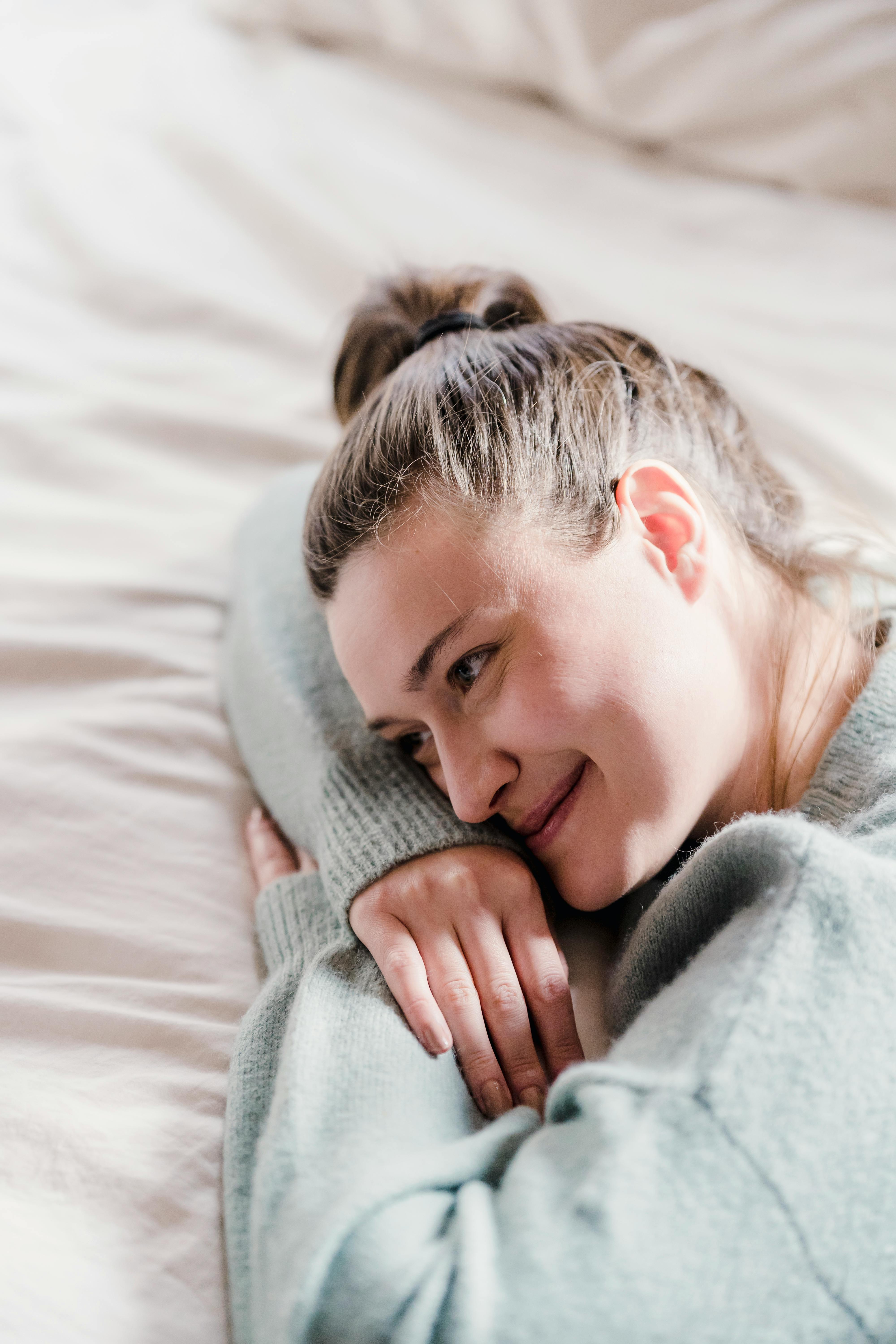 Une femme heureuse allongée sur un lit tout en pensant | Source : Pexels