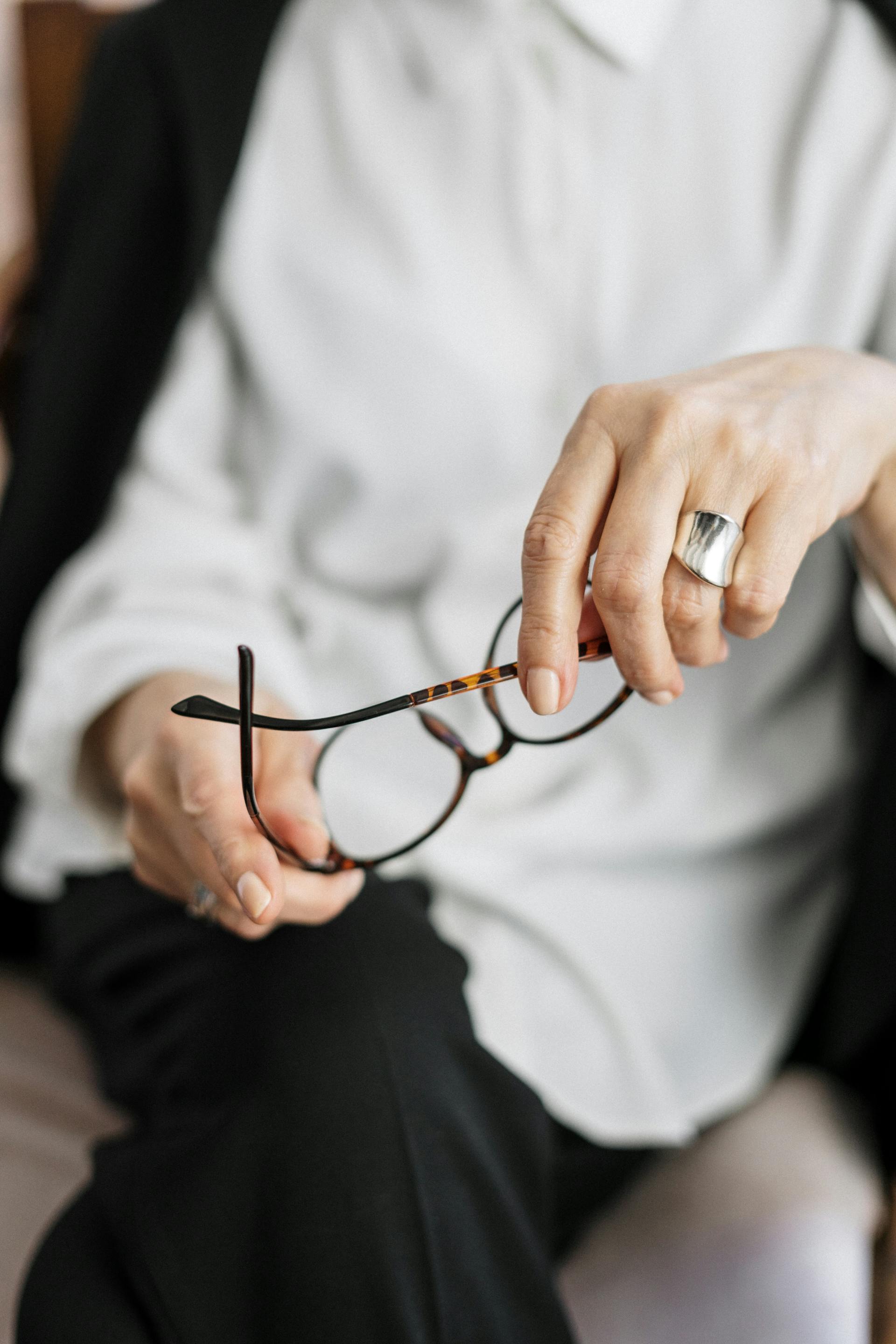 Une femme thérapeute tenant ses lunettes à monture brune | Source : Pexels