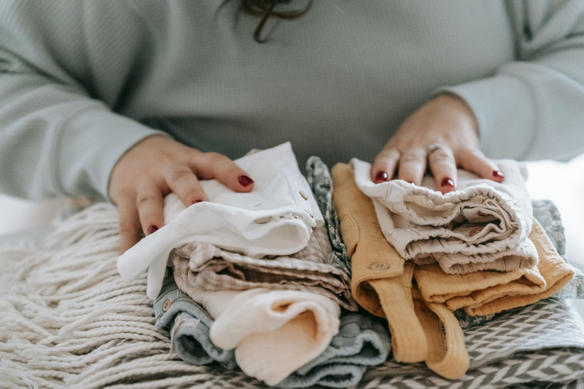 Une femme avec des vêtements de bébé pliés | Source : Pexels