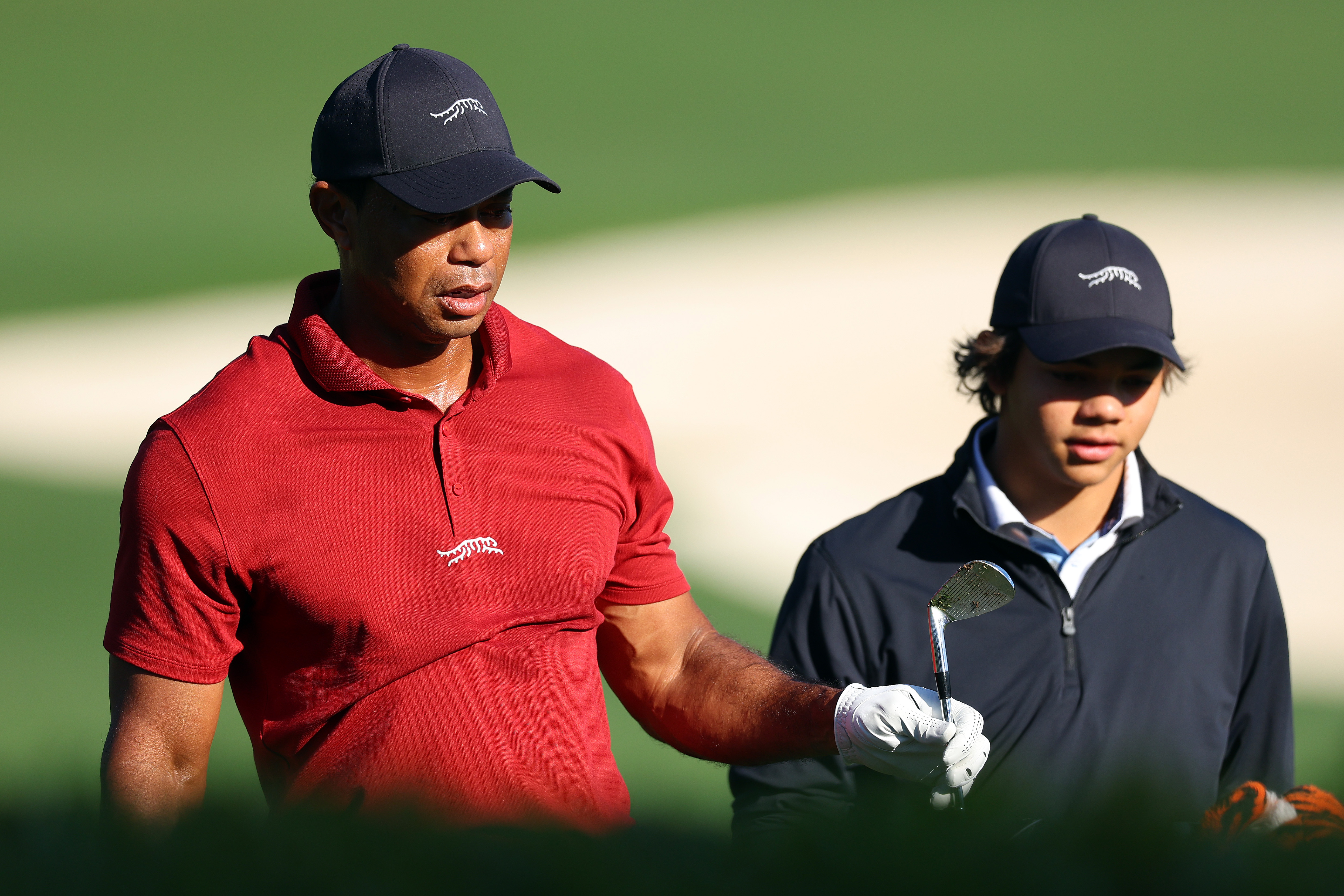 Tiger Woods s'échauffe avec Charlie Woods dans la zone d'entraînement lors du tour final du tournoi des Masters 2024 au Augusta National Golf Club en Géorgie, le 14 avril 2024. | Source : Getty Images