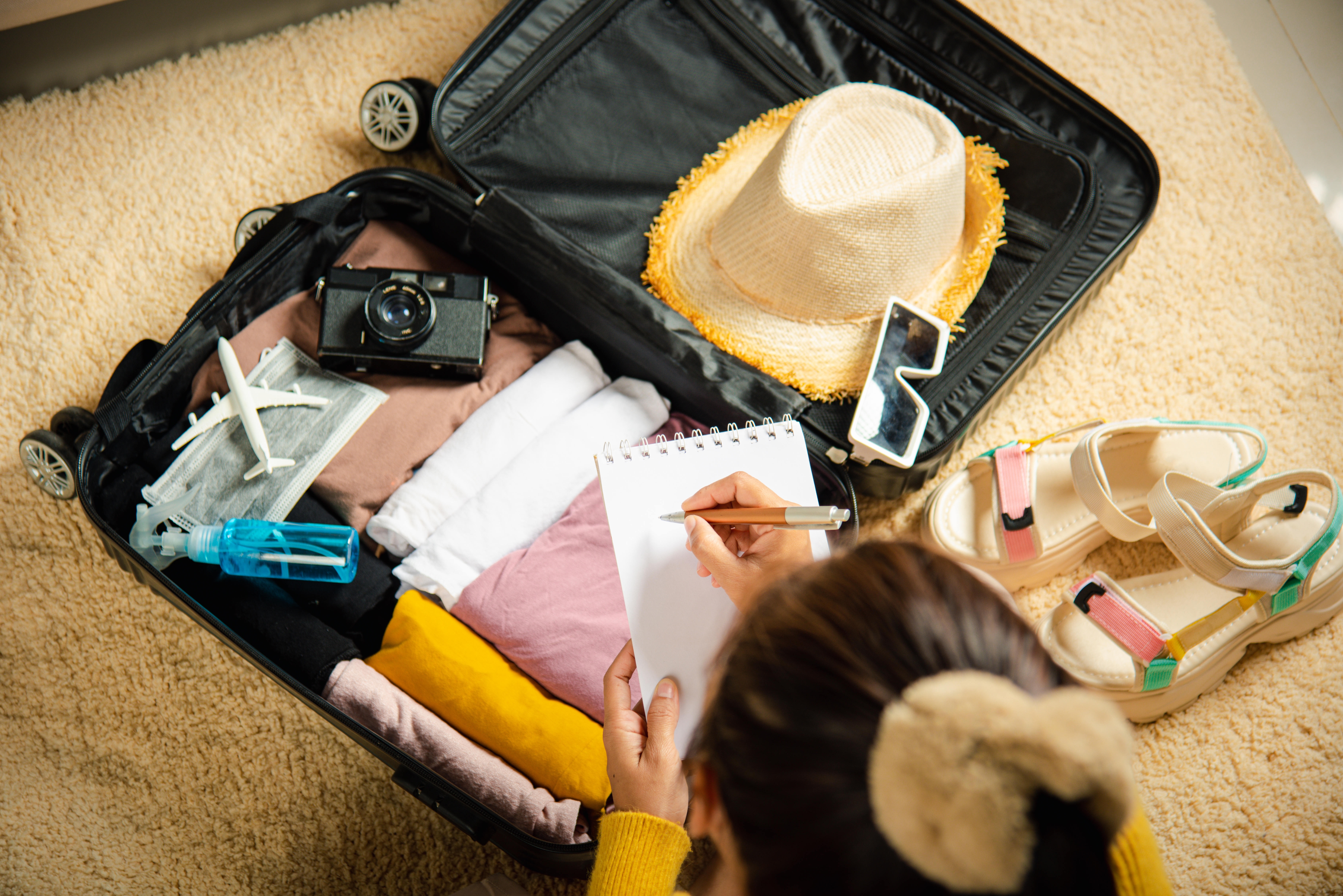 Une femme prépare une valise tout en écrivant une note | Source : Shutterstock