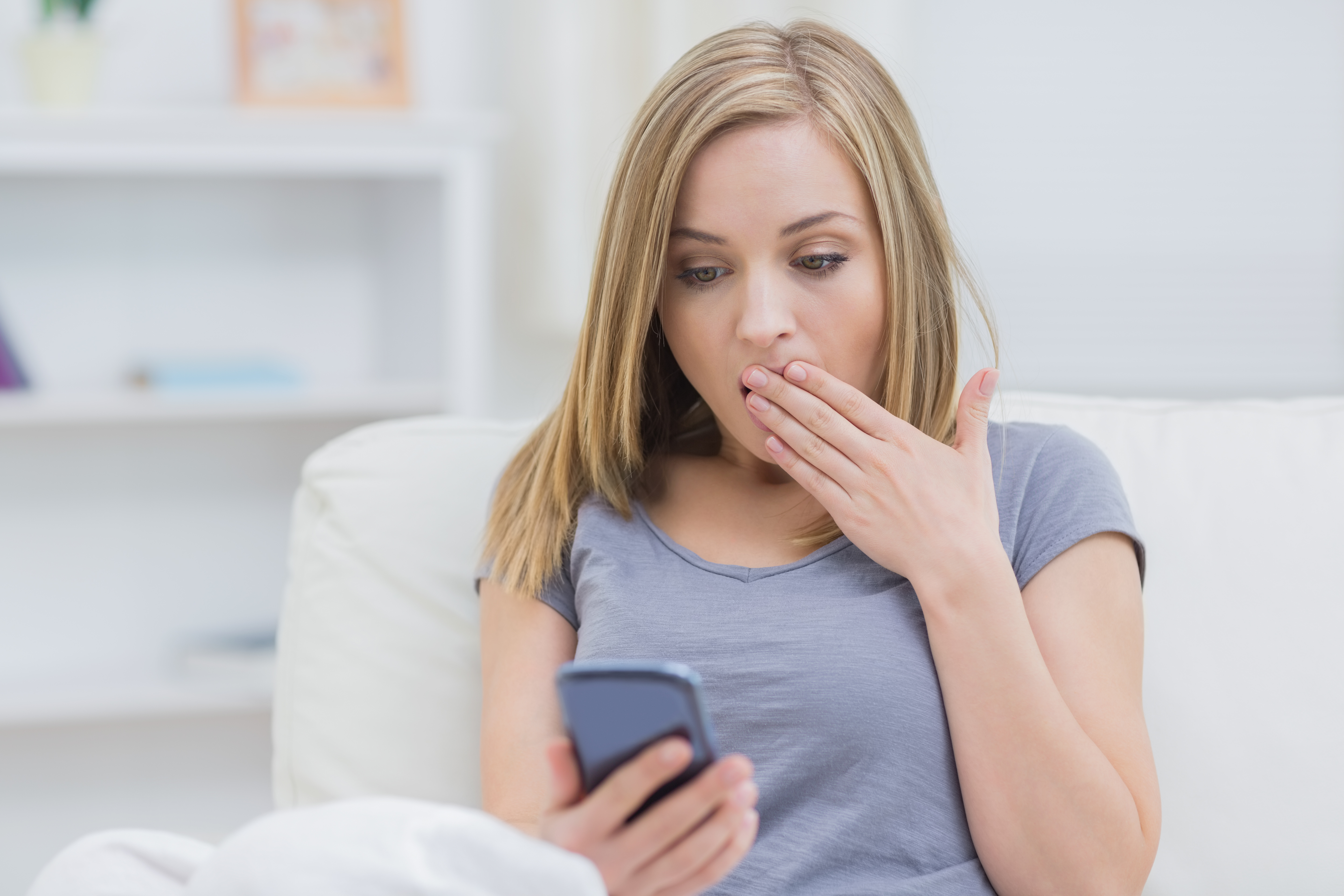Femme exprimant un choc en regardant son téléphone portable. | Source : Shutterstock