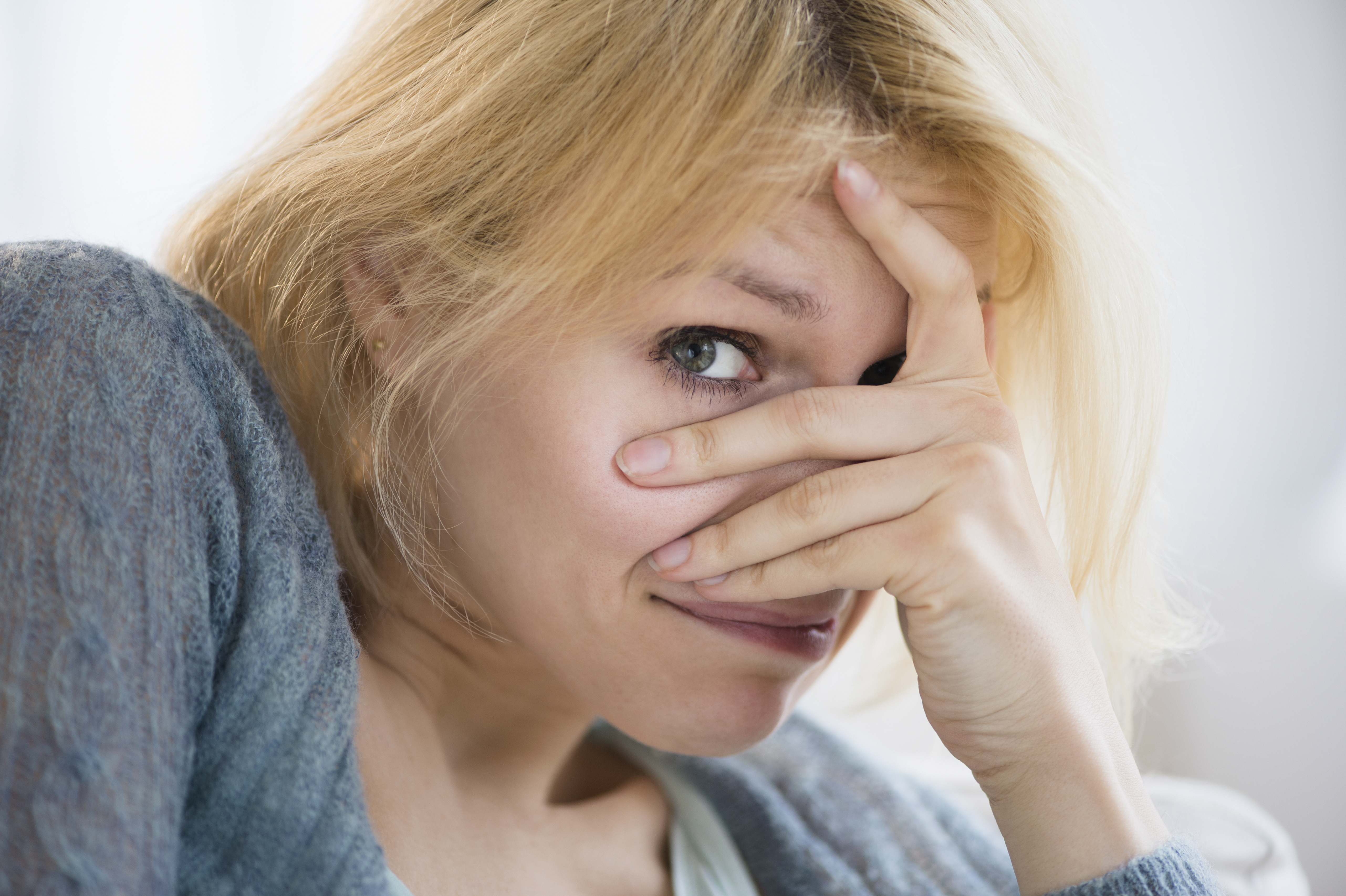 Une femme blonde troublée qui cache la moitié de son visage avec une main | Source : Getty Images