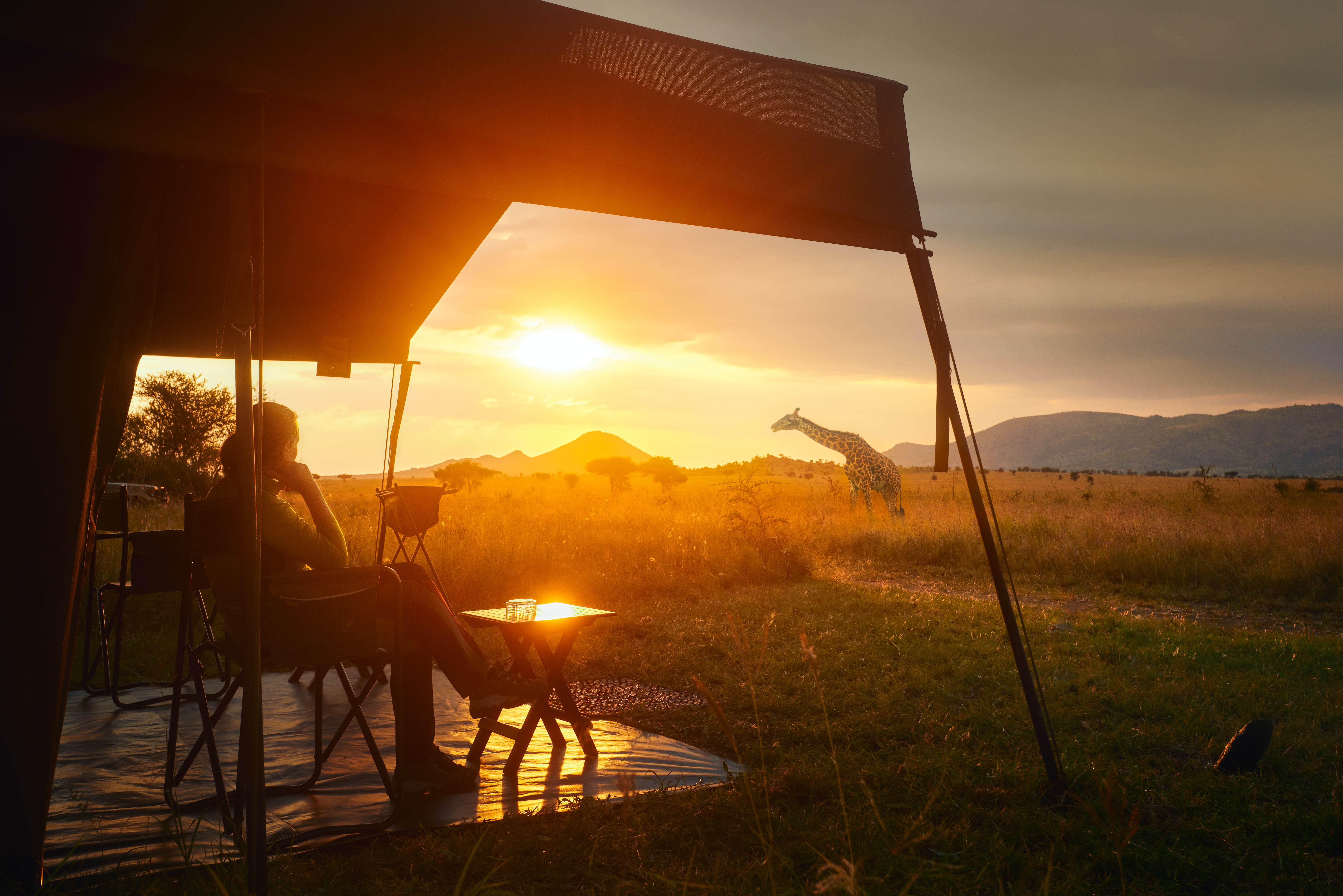 Une femme se détend dans un pavillon de safari avec une girafe en arrière-plan | Source : Shutterstock
