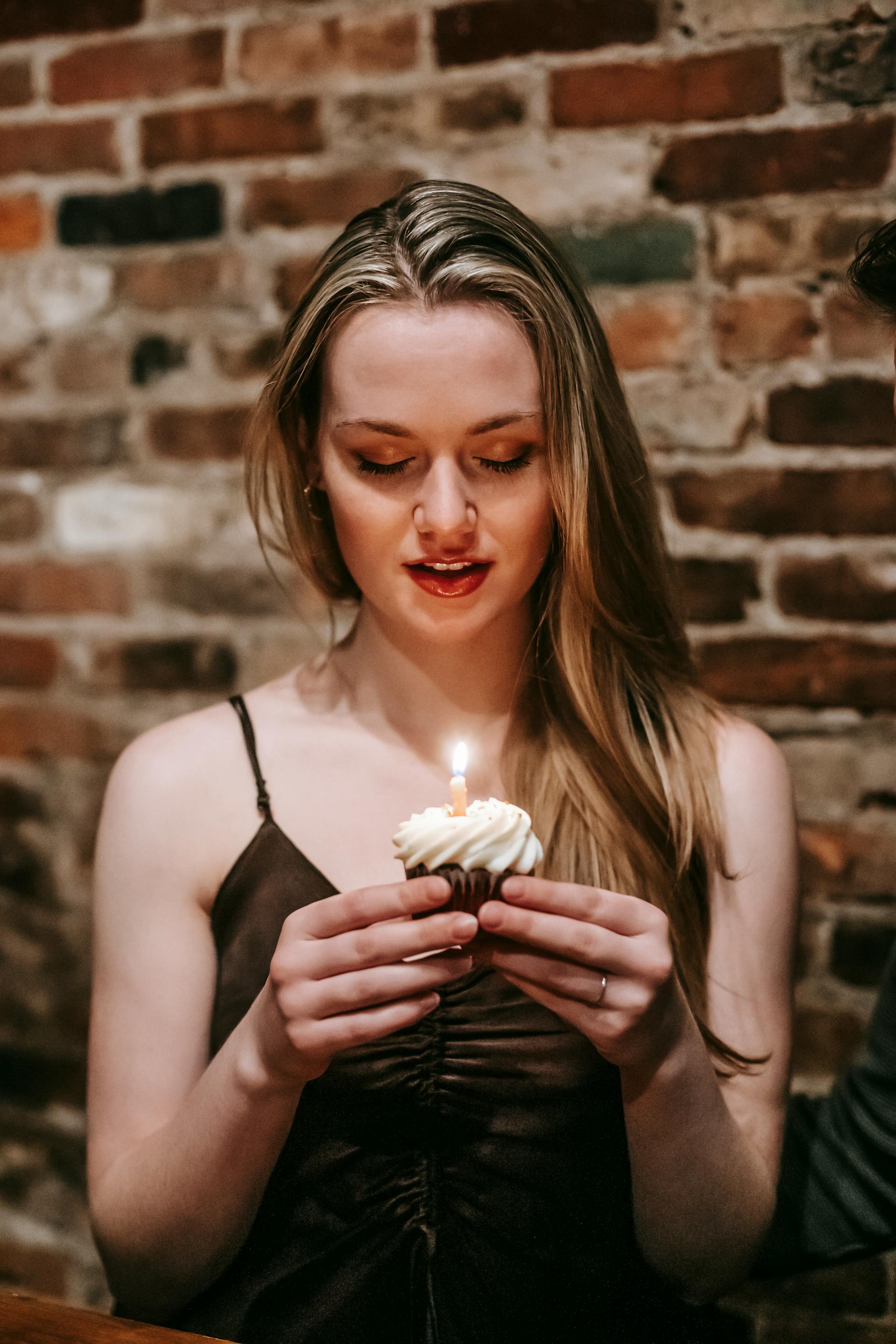 Une femme tenant un cupcake avec une bougie | Source : Pexels