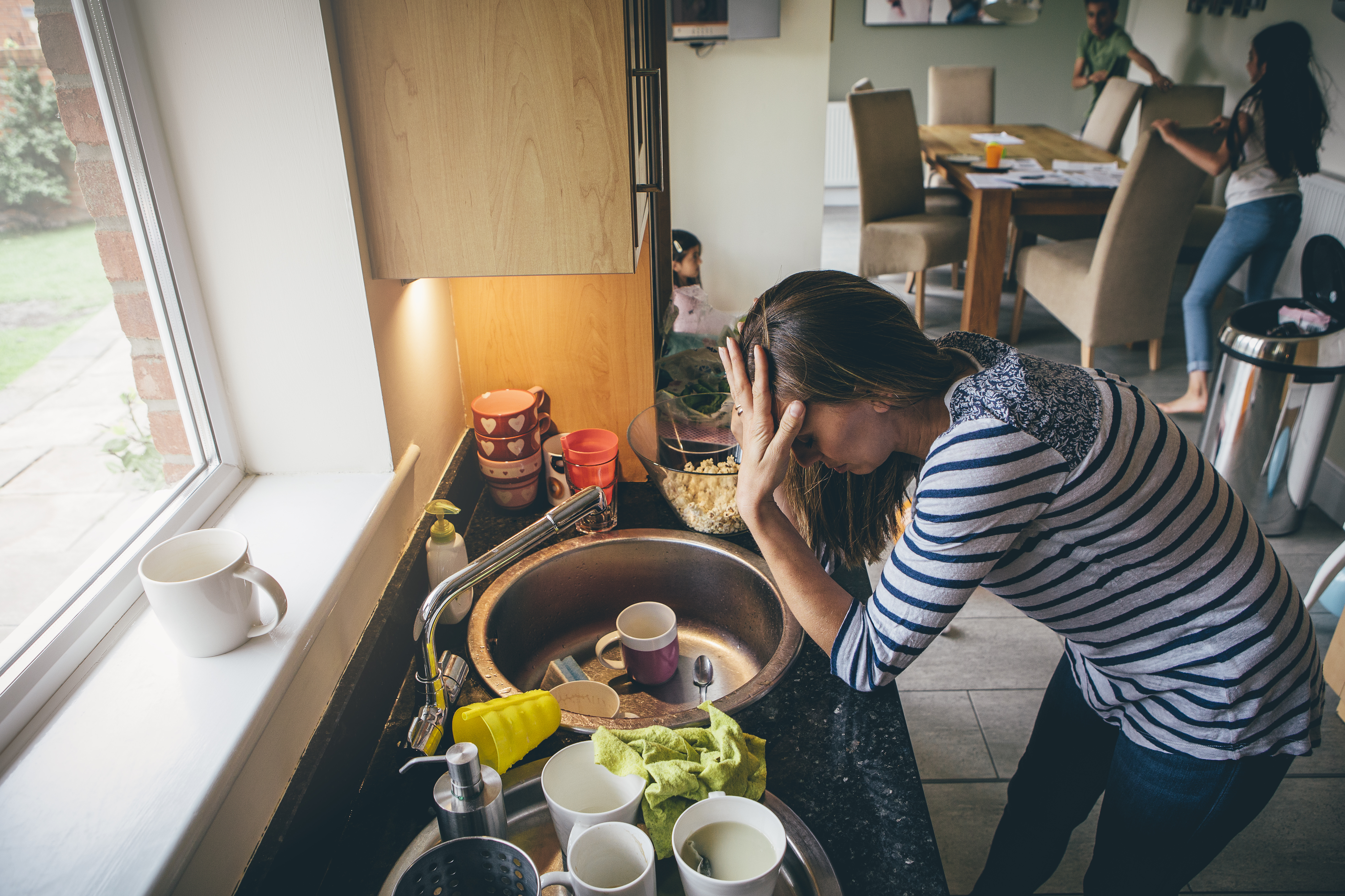 Une femme appuyée sur un comptoir de cuisine, la main sur le front | Source : Shutterstock