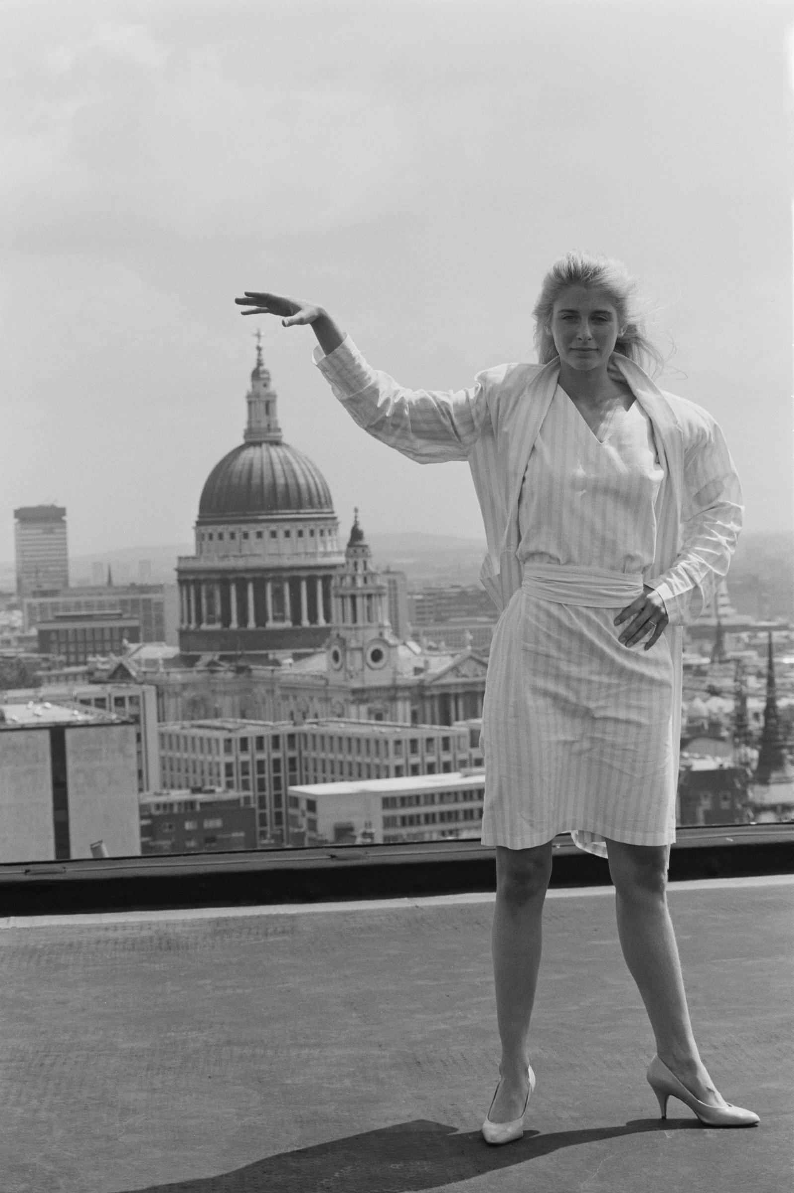 L'actrice pose sur un toit en levant la main pour l'aligner avec le sommet de la cathédrale Saint-Paul, le 16 juillet 1984 à Londres, en Angleterre. | Source : Getty Images