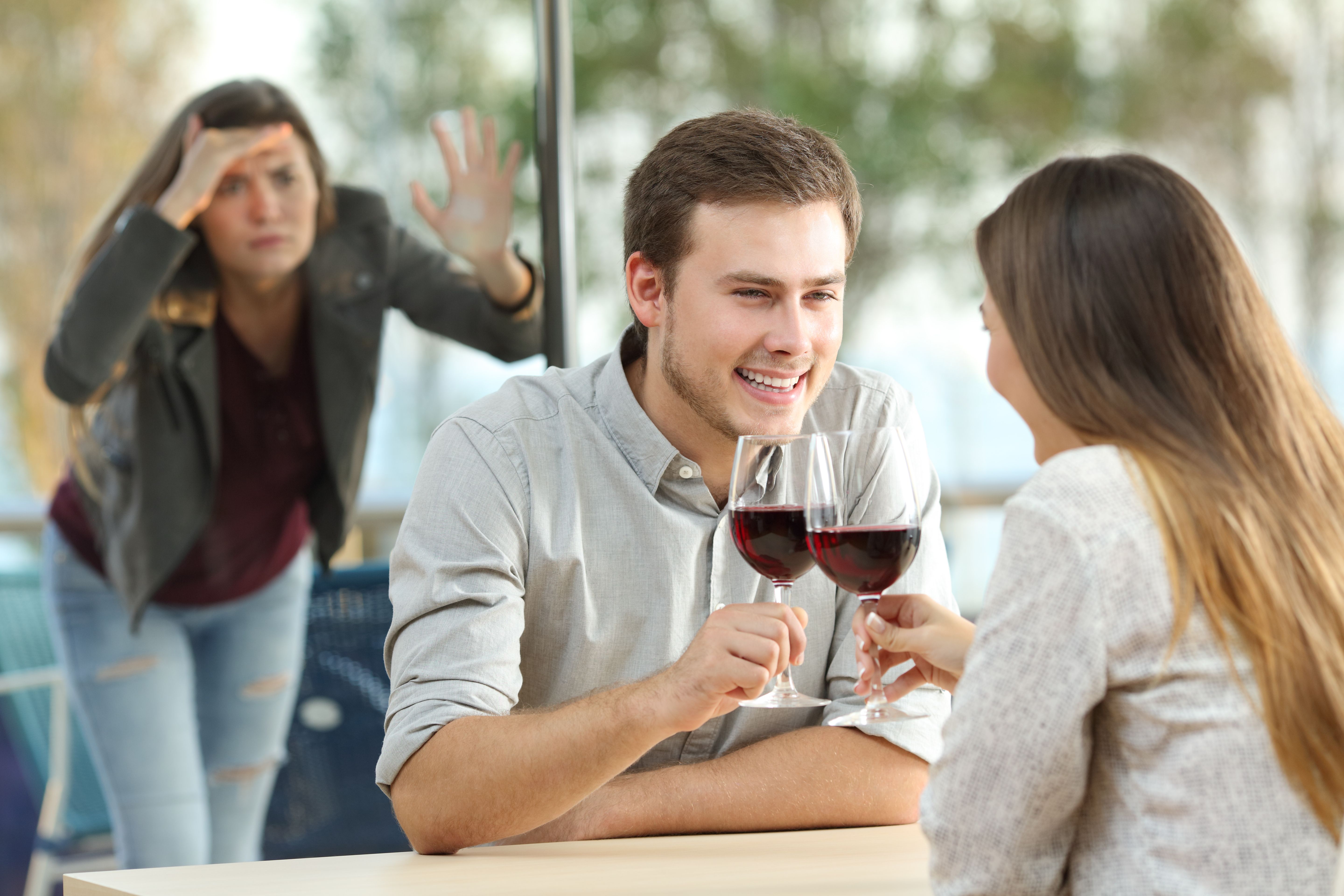 Une femme regarde par la vitre un couple en train de boire du vin | Source : Shutterstock