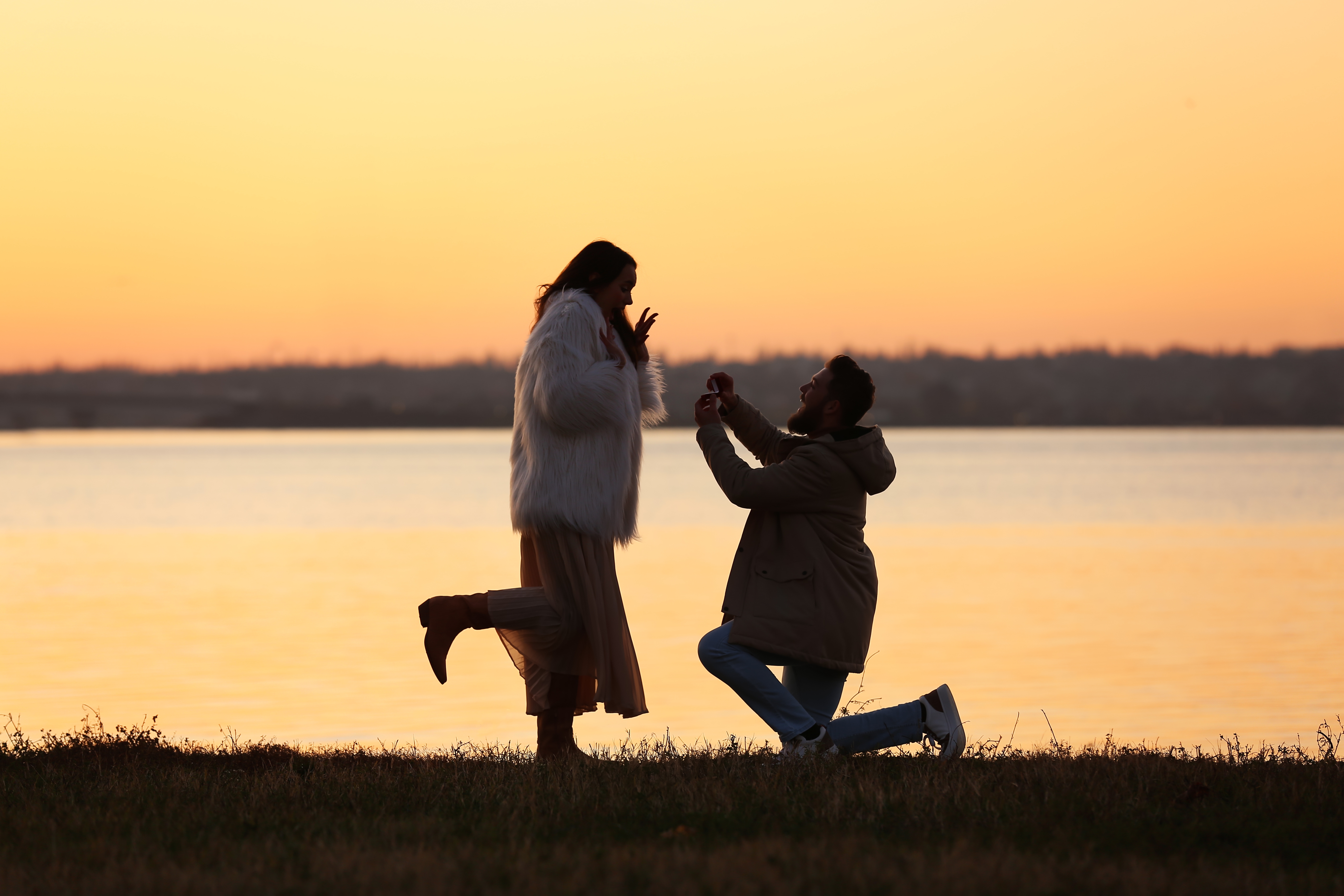 Homme demandant sa petite amie en mariage près d'une rivière pendant le coucher du soleil | Source : Shutterstock