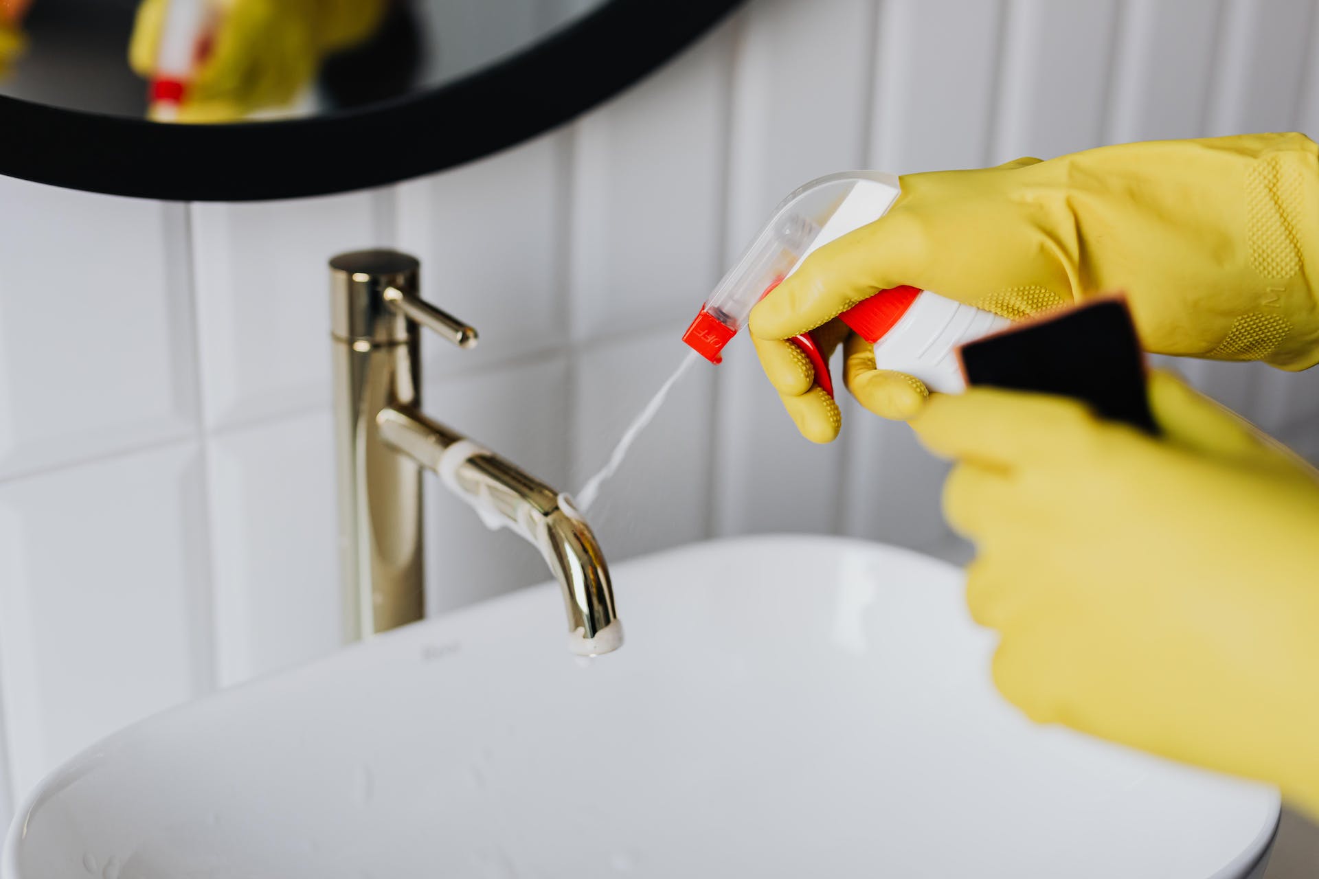 Personne nettoyant la salle de bain avec des gants jaunes | Source : Pexels
