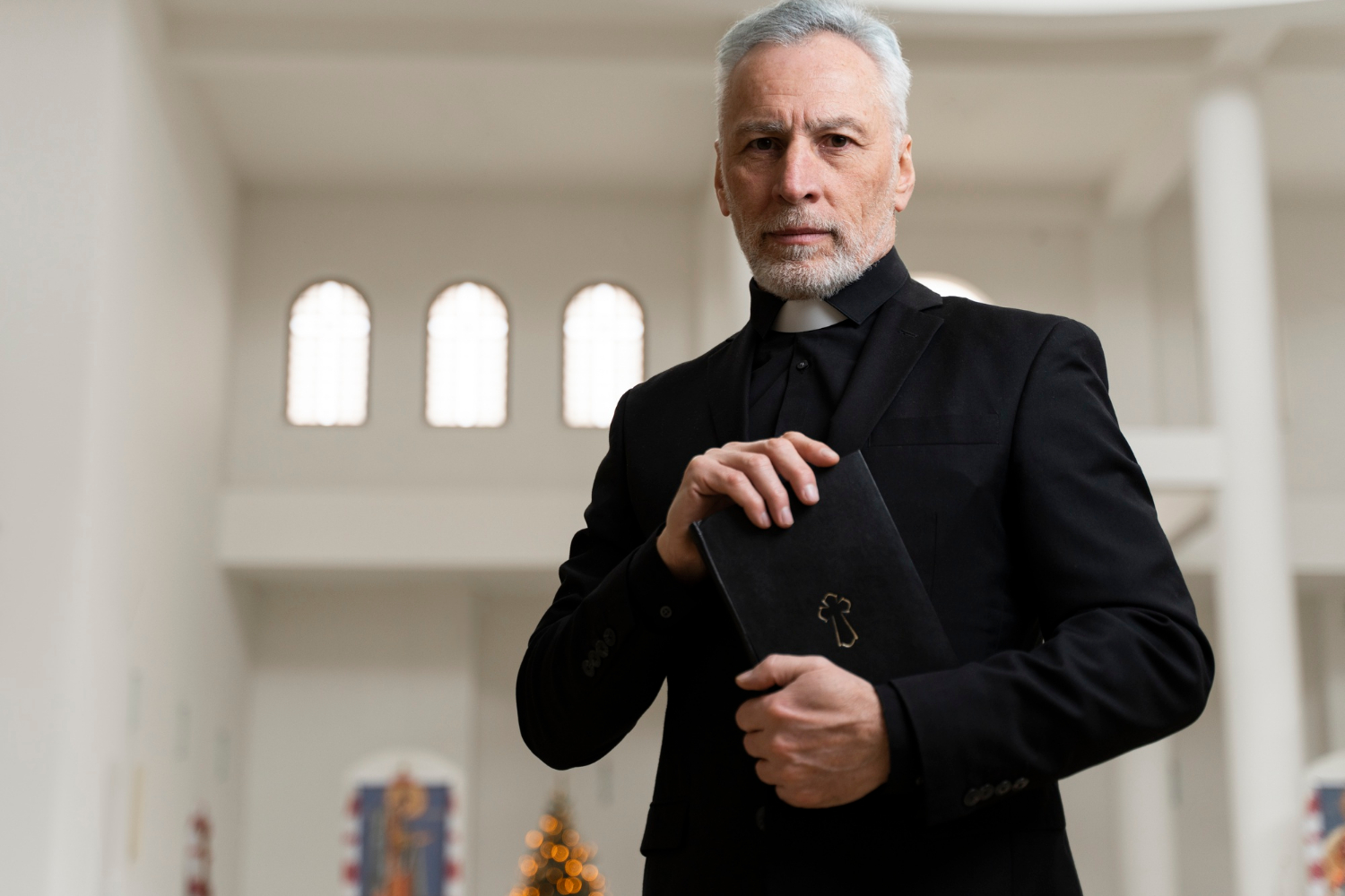 Un prêtre tenant un livre saint | Source : Freepik