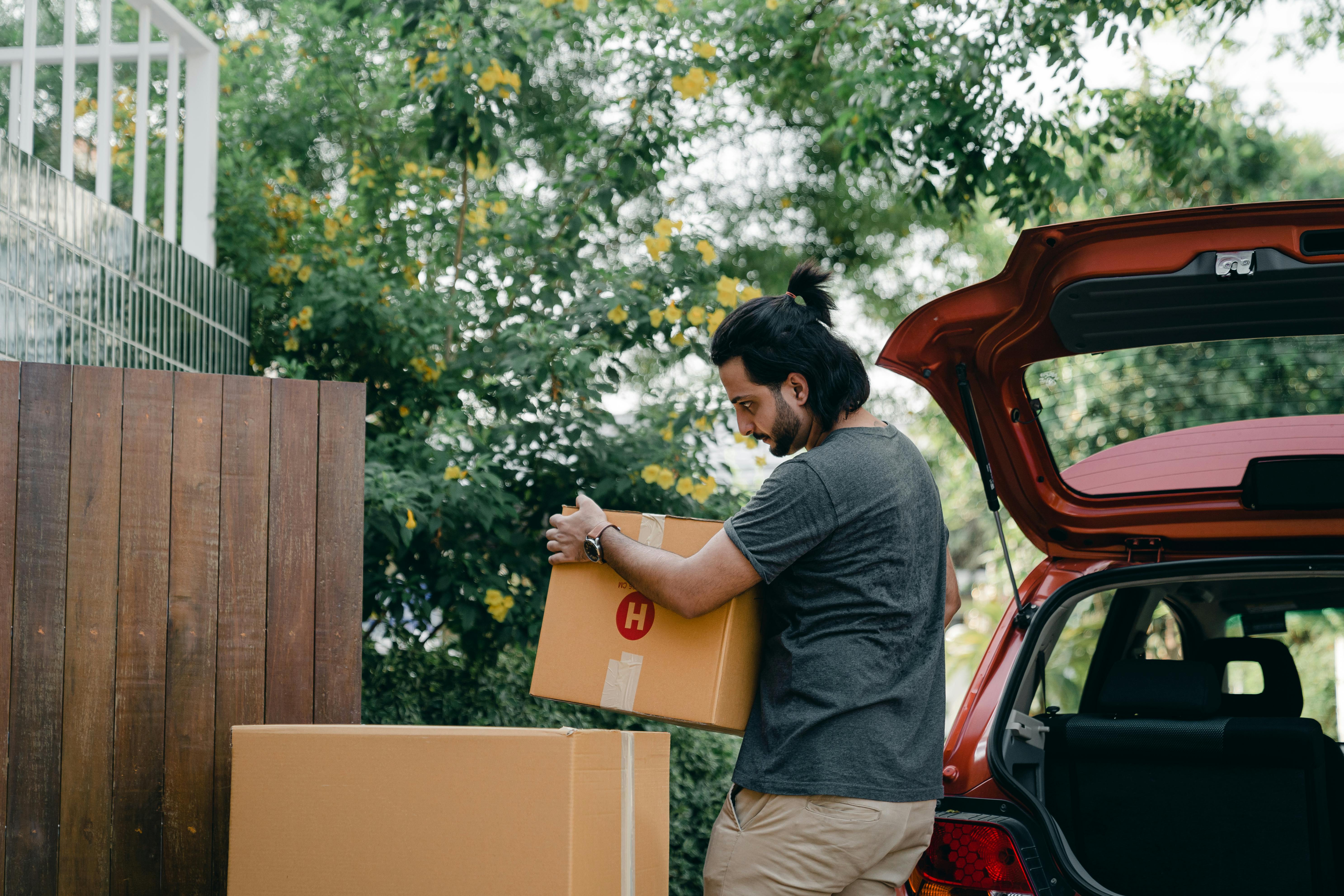 Un homme emballe des cartons de déménagement dans une voiture | Source : Pexels