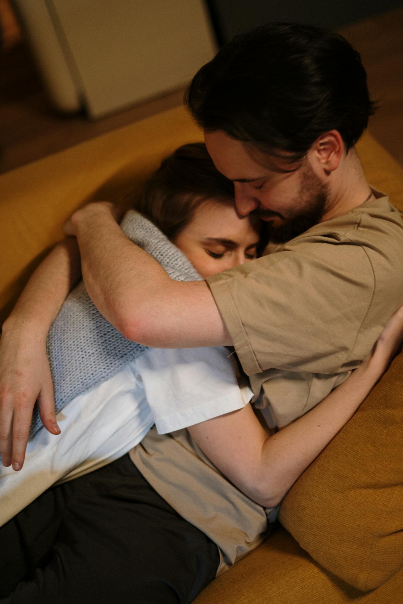 Un couple qui se prend dans les bras alors qu'il est allongé sur le canapé | Source : Pexels