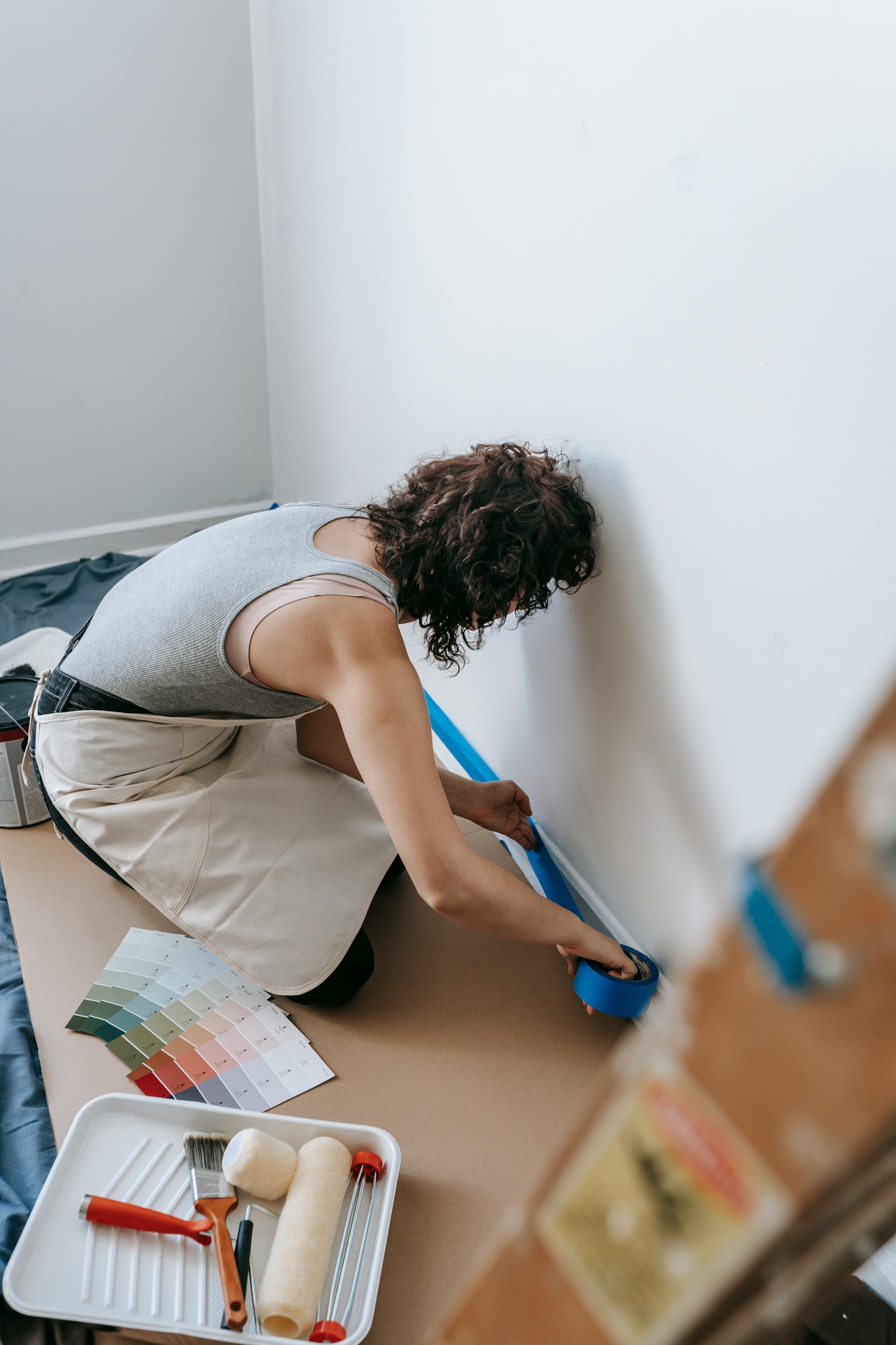 Une femme qui se prépare à peindre en scotchant le mur | Source : Pexels