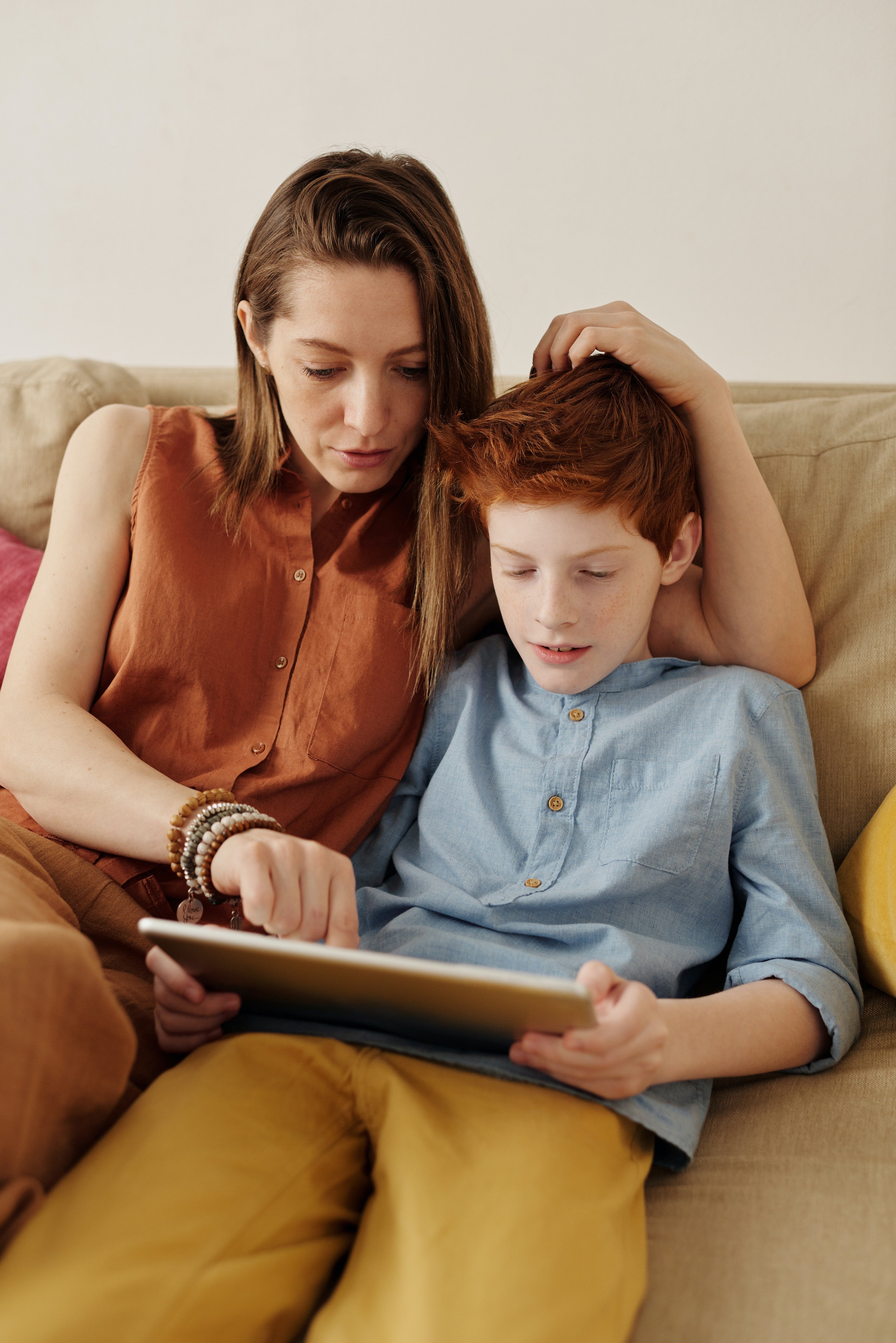 Une femme et un enfant assissent et entraine de regarder quelque chose sur une tablette. | Photo : Pexels