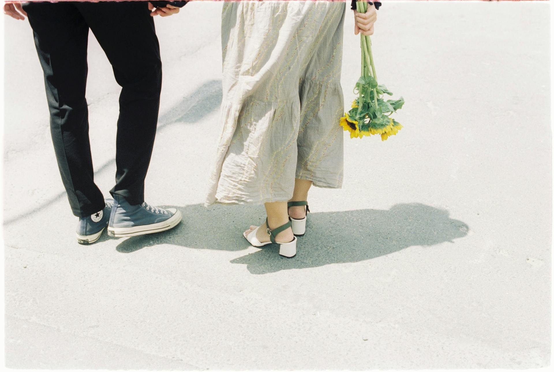 Une femme tenant un bouquet de tournesols et marchant avec son partenaire | Source : Pexels