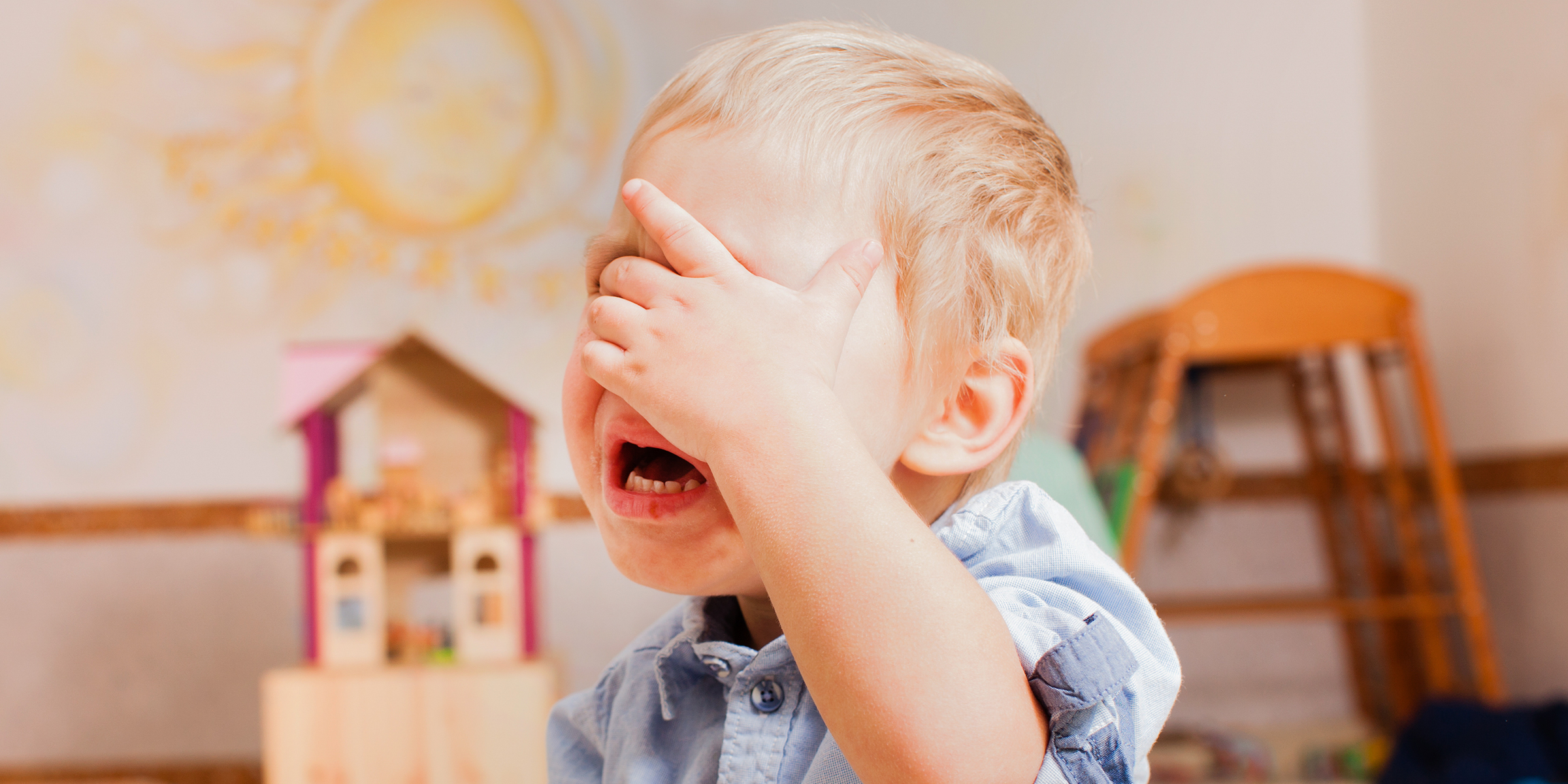 Un petit garçon qui se couvre le visage en pleurant | Source : Shutterstock