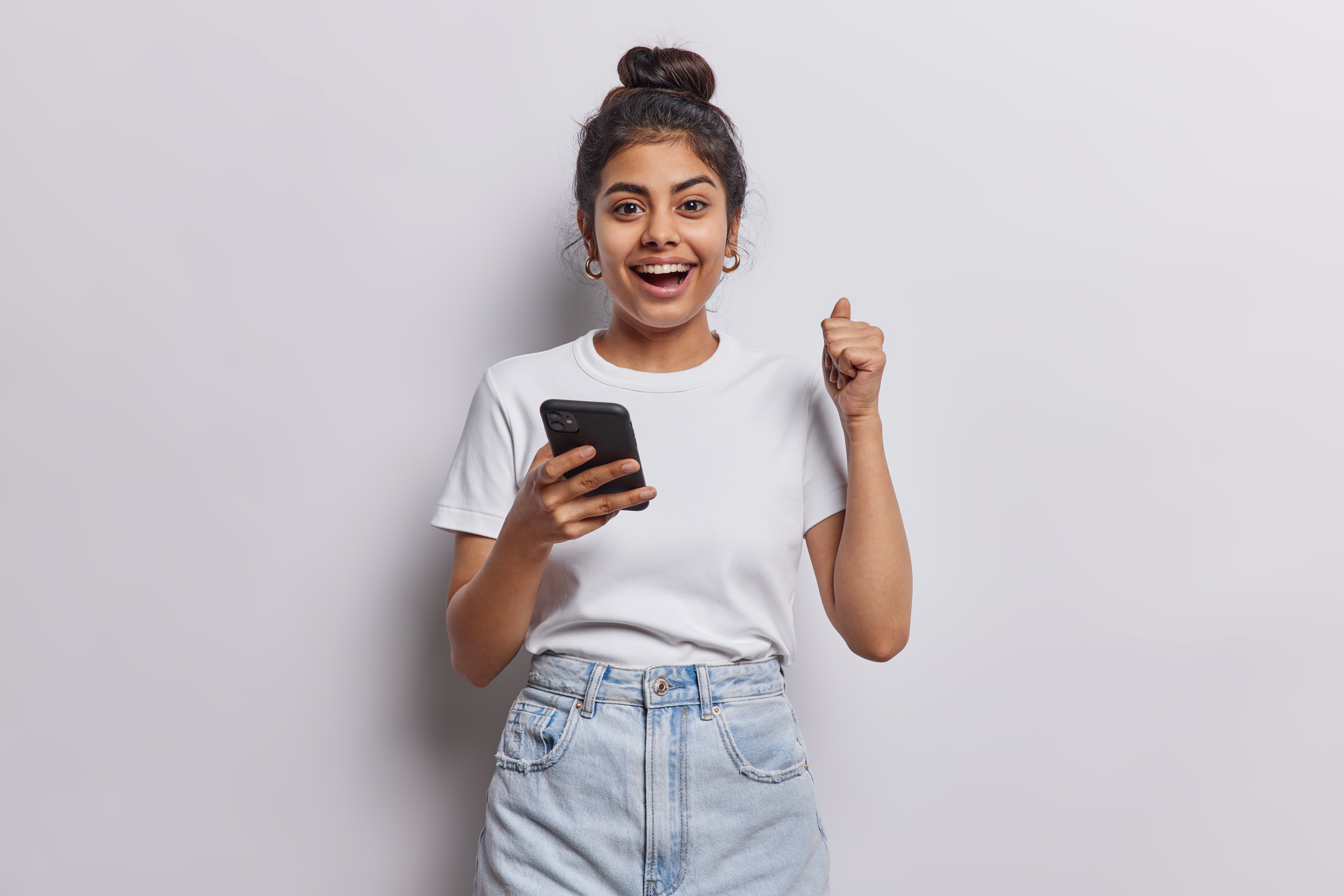 Jeune femme joyeuse montrant un pouce levé alors qu'elle est sur son téléphone | Source : Shutterstock