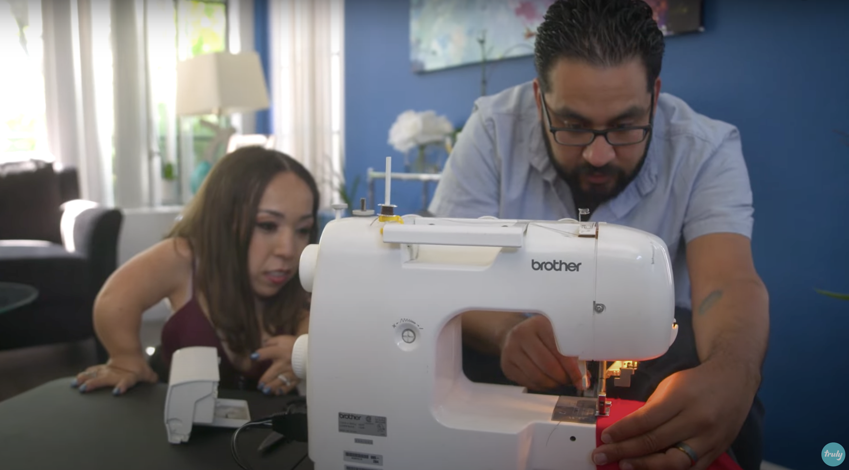 Bryan utilise une machine à coudre pour apporter des modifications à la chemise de Yesi | Source : Youtube.com/Truly