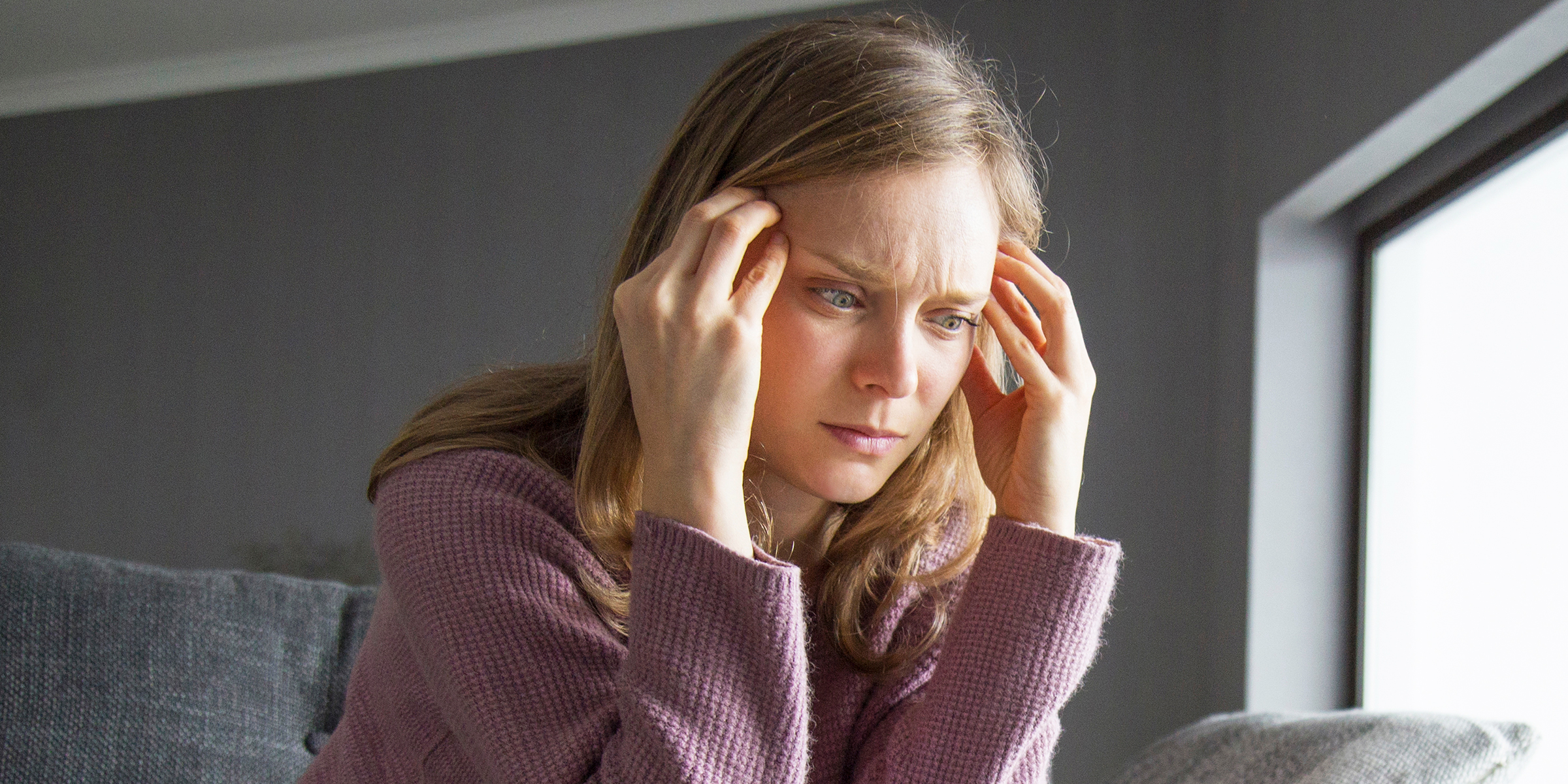 Une femme inquiète presse ses doigts sur ses tempes | Source : Shutterstock