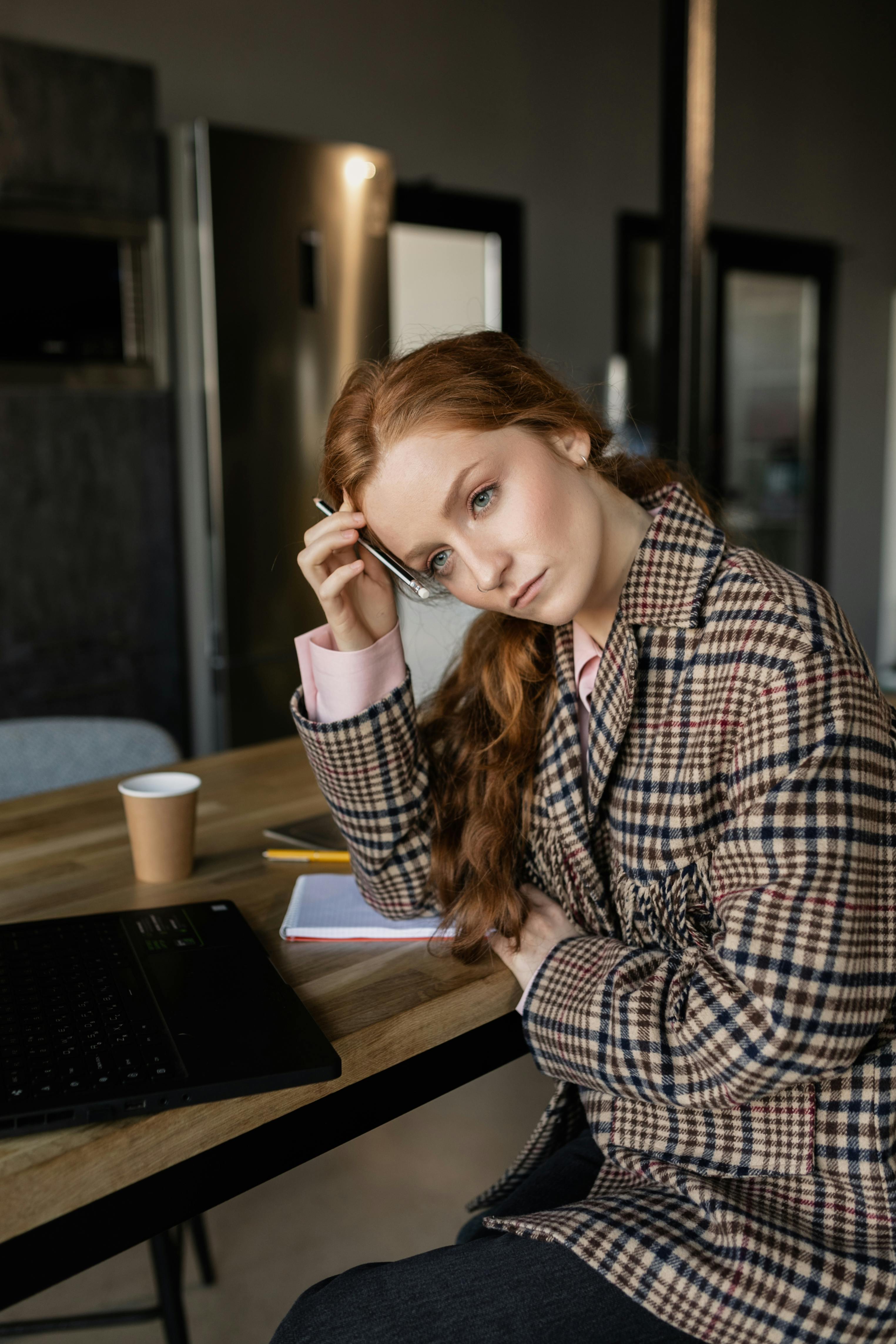 Une femme inquiète en tailleur marron assise à une table | Source : Pexels