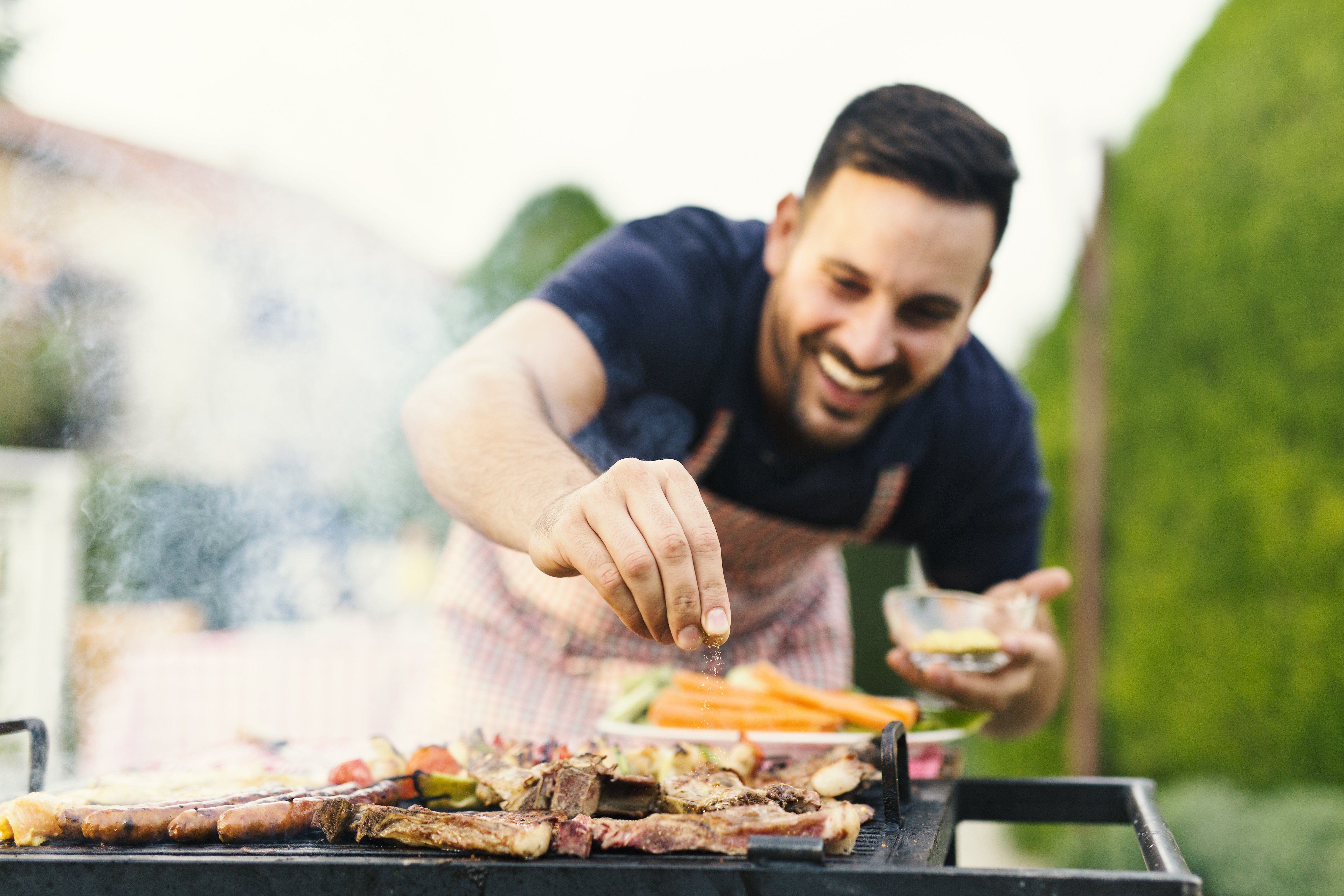 Un homme assaisonnant de la viande | Photo : Shutterstock