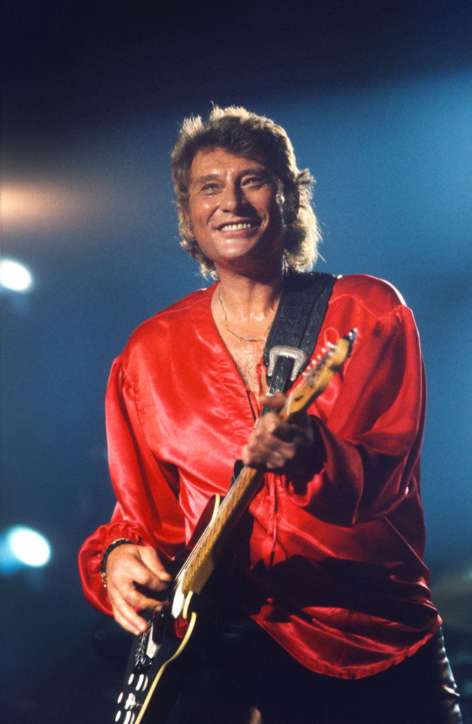 Johnny Halliday se produit au Forest National, Bruxelles, Belgique, le 26 juin 1993. Il porte un vêtement rouge et joue de la guitare.