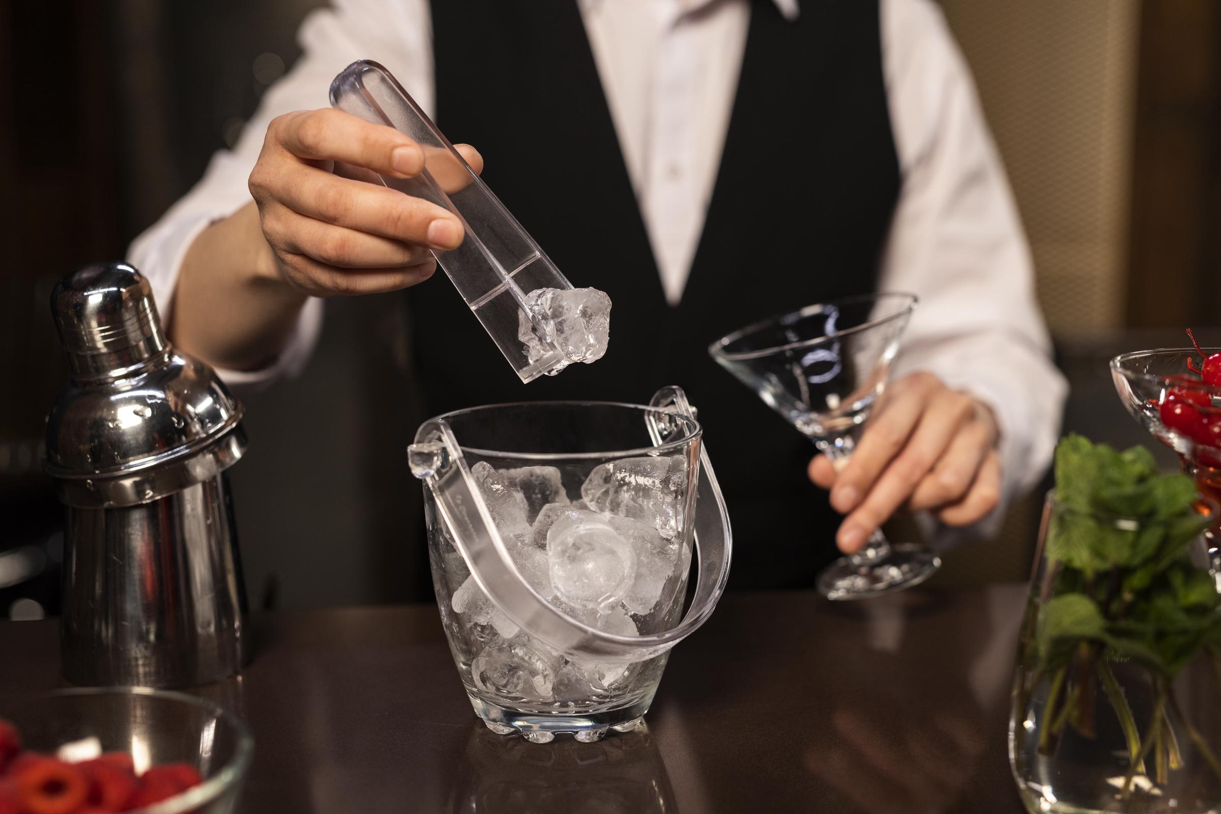 Un employé de restaurant prépare une boisson avec des glaçons | Source : Freepik