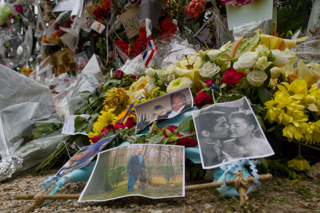 Cette photographie montre des photos de l'acteur français Alain Delon au milieu de fleurs déposées par des fans à la porte d'entrée de la propriété de Delon, La Brulerie, à Douchy, dans le centre de la France, le 23 août 2024, à la veille de ses funérailles. | Source : Getty Images