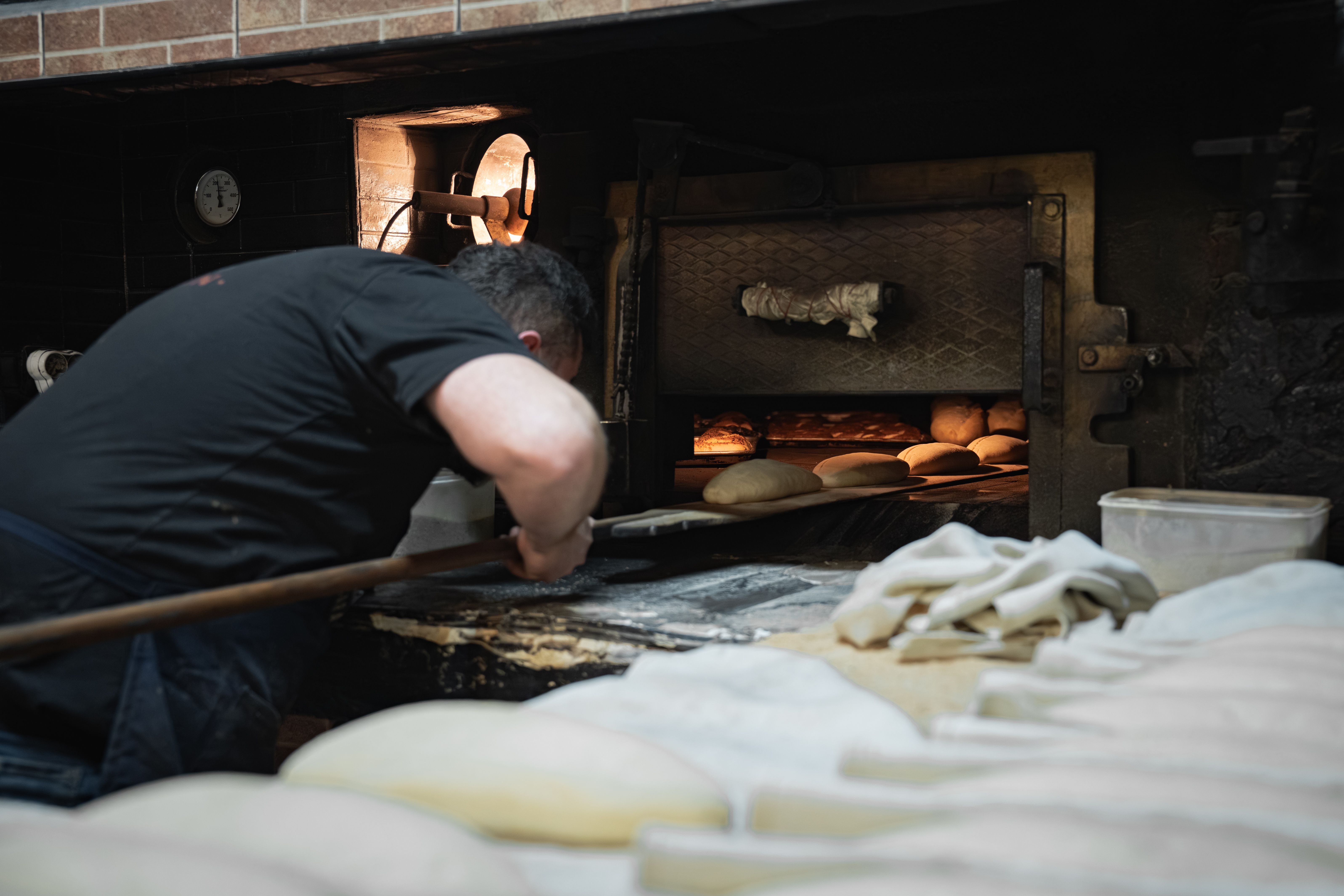 Un boulanger met des miches dans un four à bois rustique | Source : Pexels