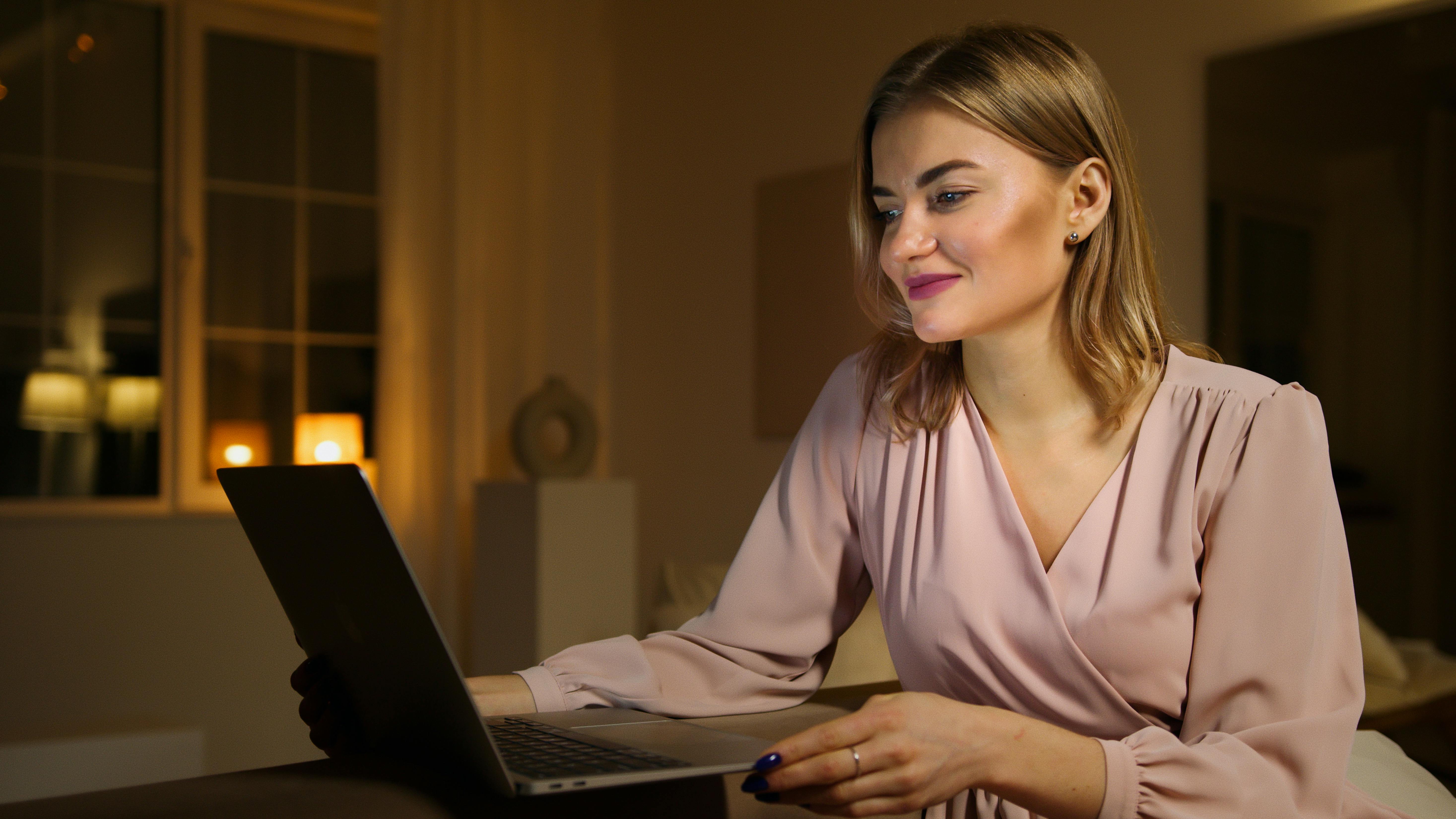 Une femme qui regarde un ordinateur portable en souriant | Source : Pexels