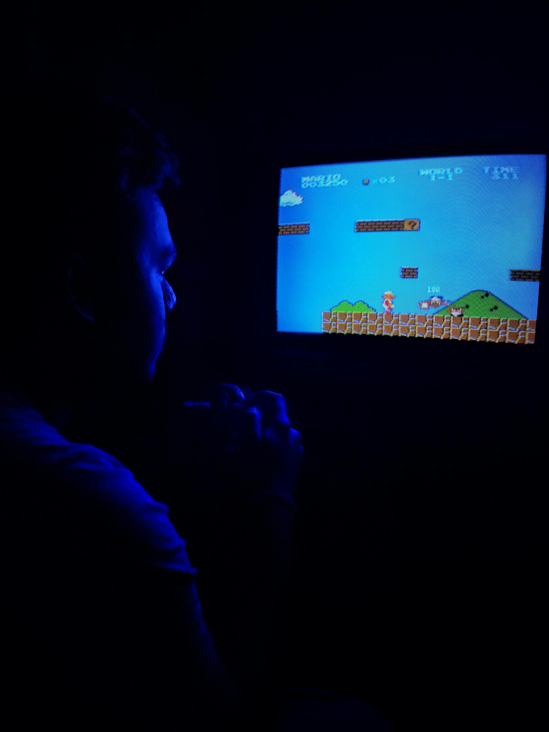 Un homme qui joue à des jeux vidéo dans l'obscurité | Source : Pexels