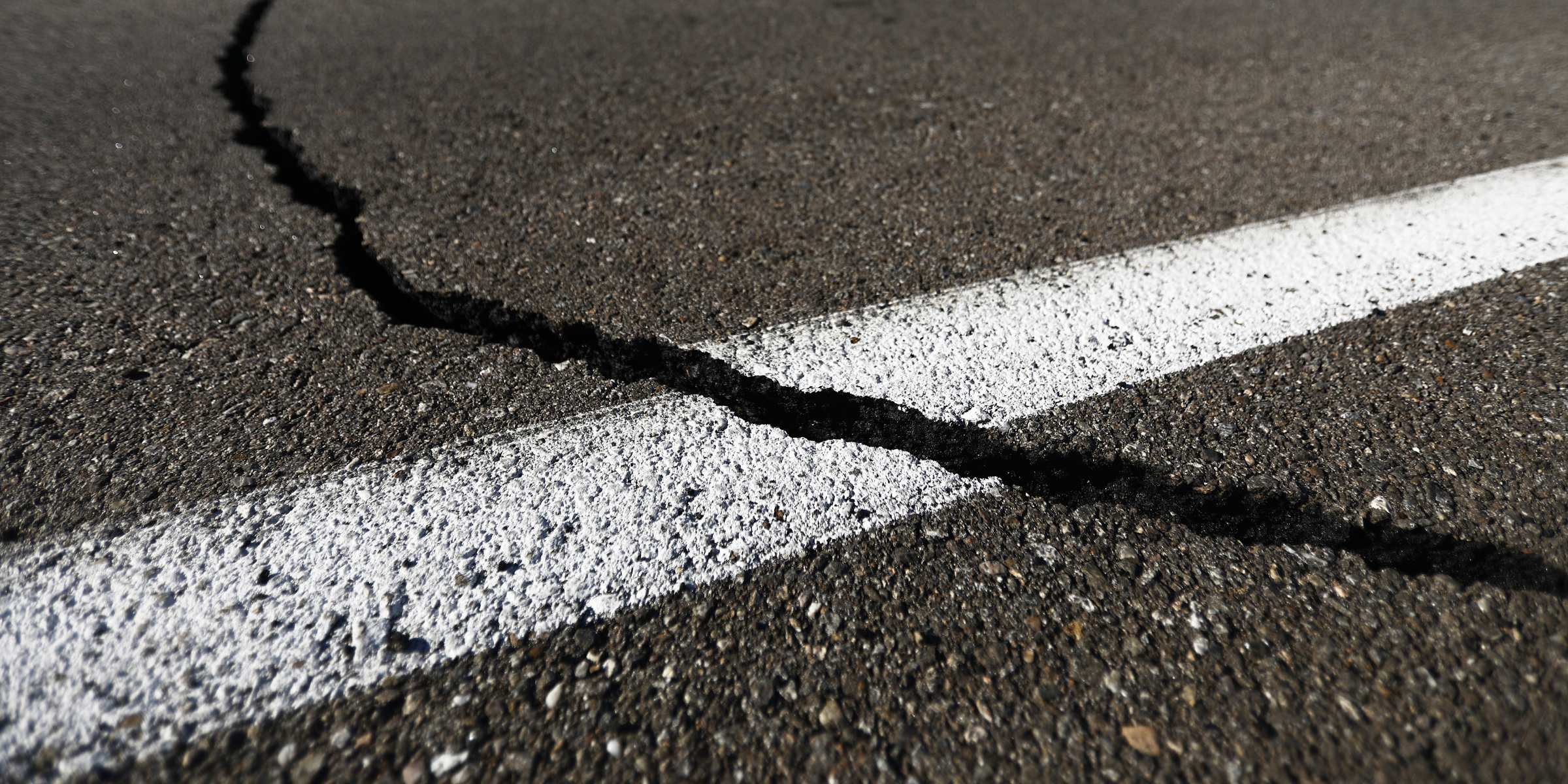 Gros plan sur une route en asphalte fissurée | Source : Getty Images