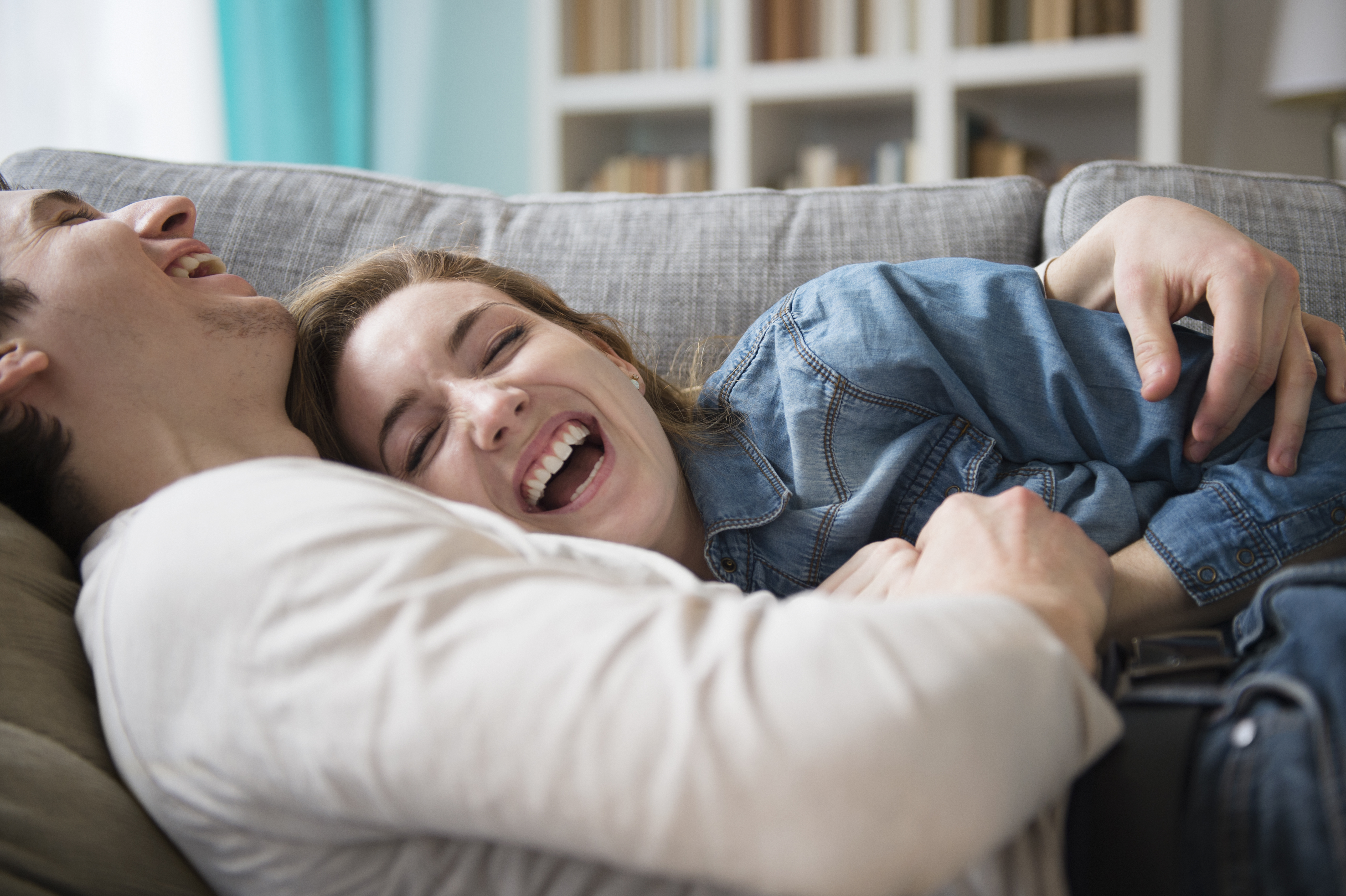 Un couple riant ensemble sur le canapé | Source : Getty Images