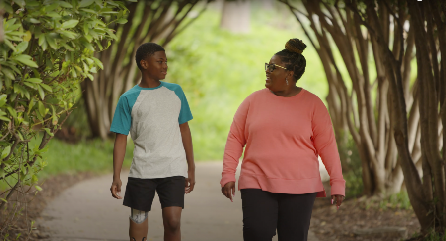 Capture d'écran d'une vidéo YouTube de Parker et de sa mère se promenant dans un parc, postée le 6 juillet 2022 | Source : YouTube.com/Shriners Children's