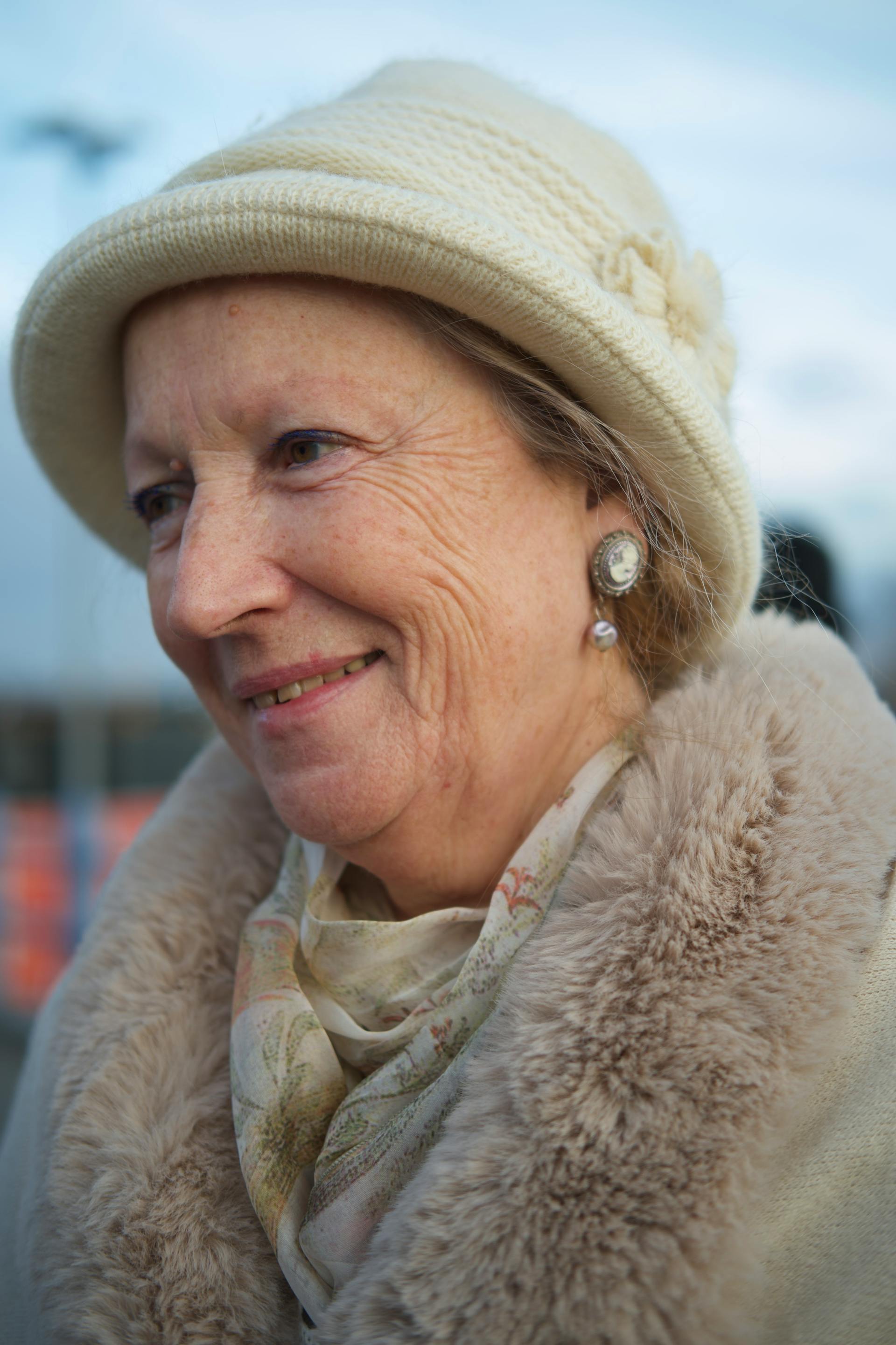 Une femme âgée souriante vêtue d'un manteau de fourrure blanc et d'un bonnet tricoté. | Source : Pexels