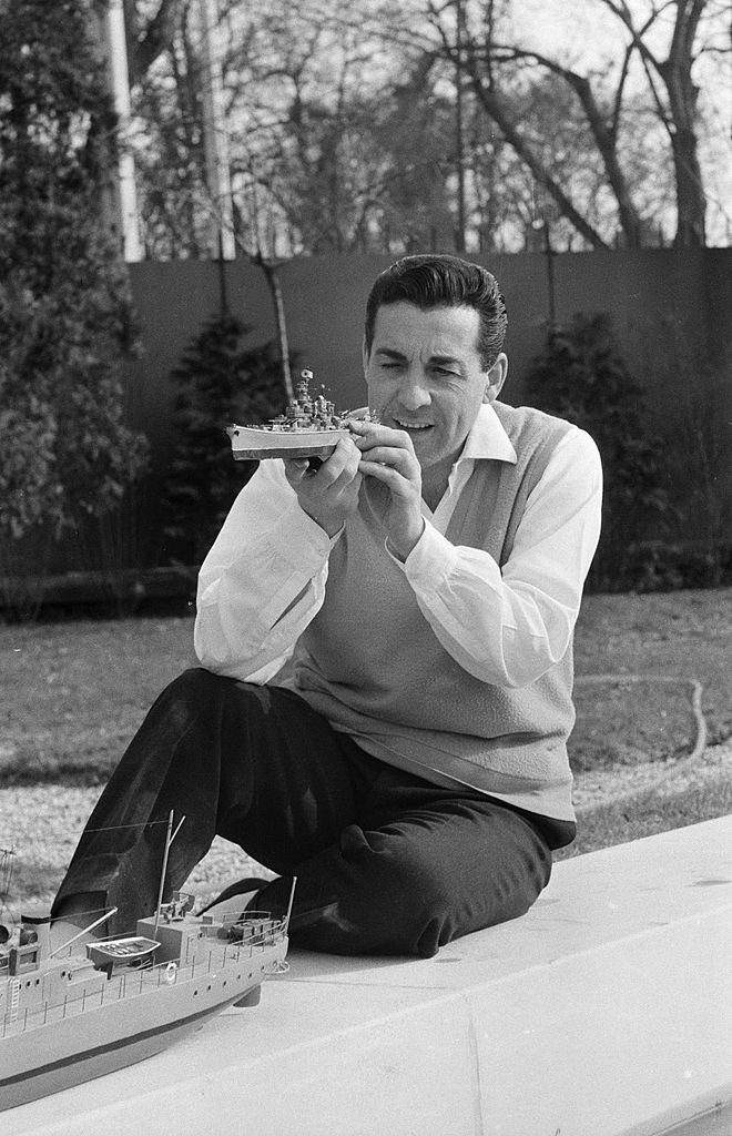 Le 14 avril 1956, le chanteur Luis Mariano dans sa maison du Vesinet, Au bord de la piscine, il joue avec une maquette de bateau. | Photo : Getty Images