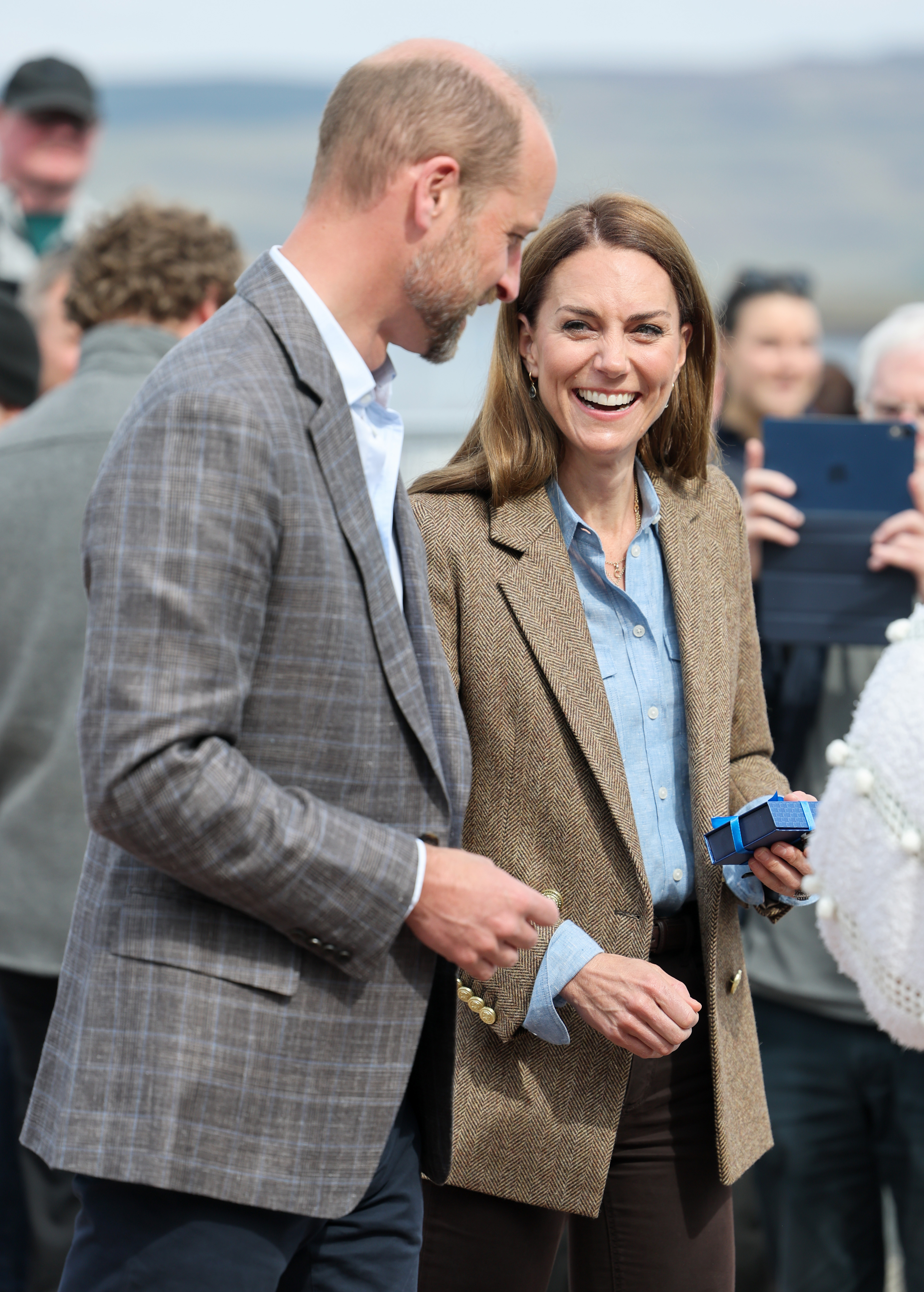 Catherine sourit en tenant un petit cadeau aux côtés de William lors d'un engagement communautaire à Tobermory. L'attitude avenante du couple s'est manifestée lors de leur visite à Aros Hall, où ils se sont mêlés aux résidents.