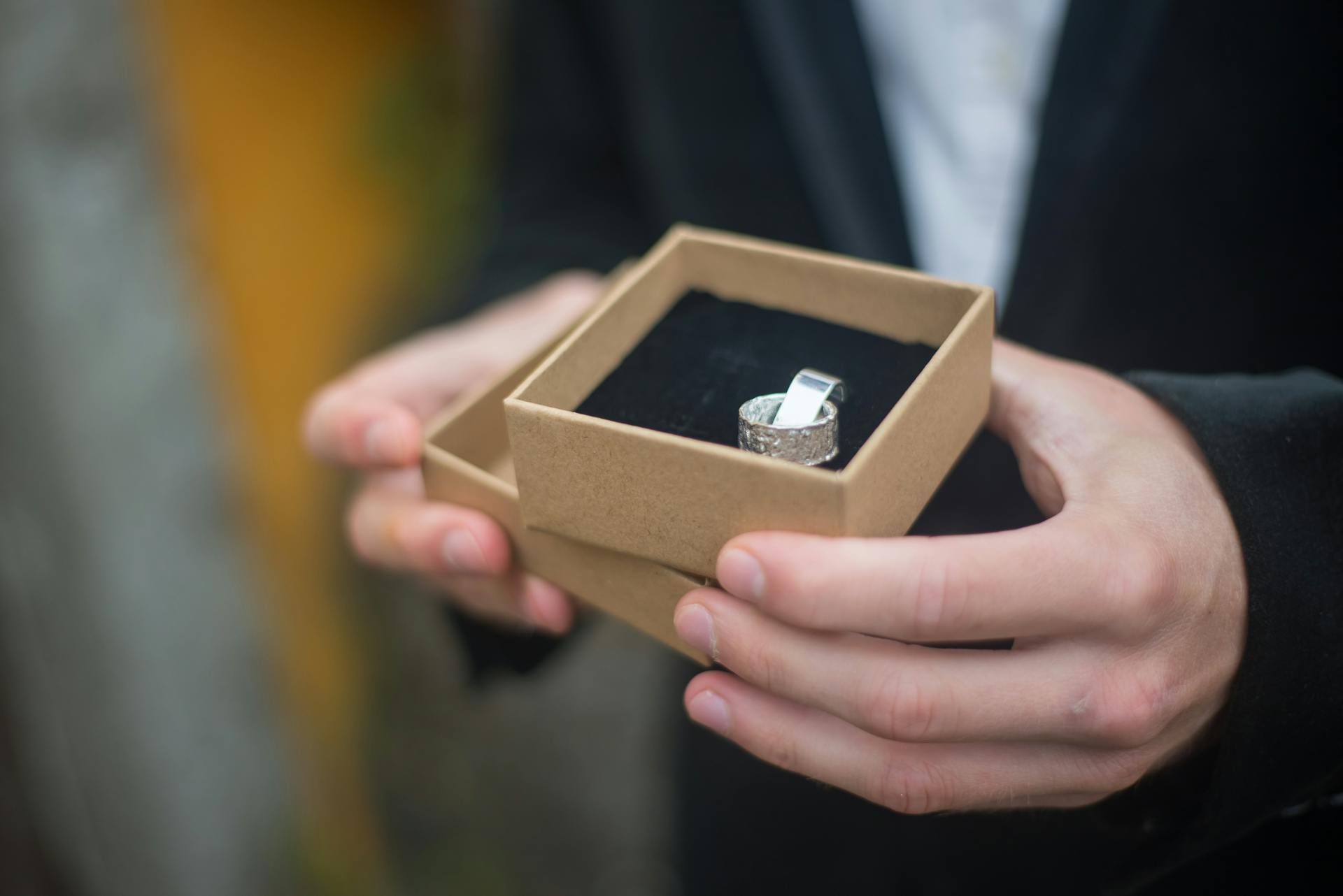 Gros plan recadré d'un homme tenant une boîte brune avec une bague | Source : Pexels