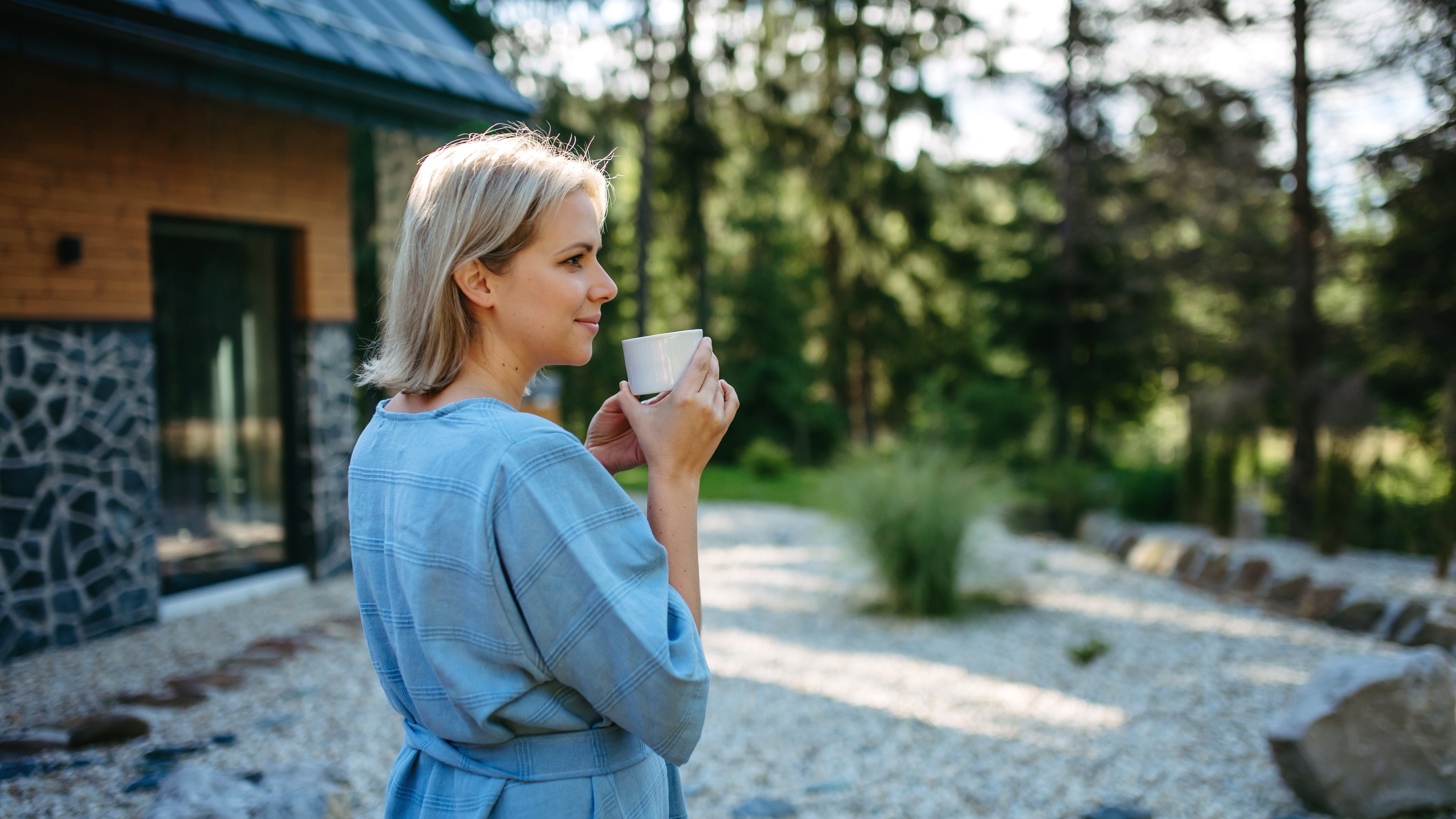 Une femme savourant une tasse de café dans un jardin à l'extérieur de sa maison | Source : Shutterstock