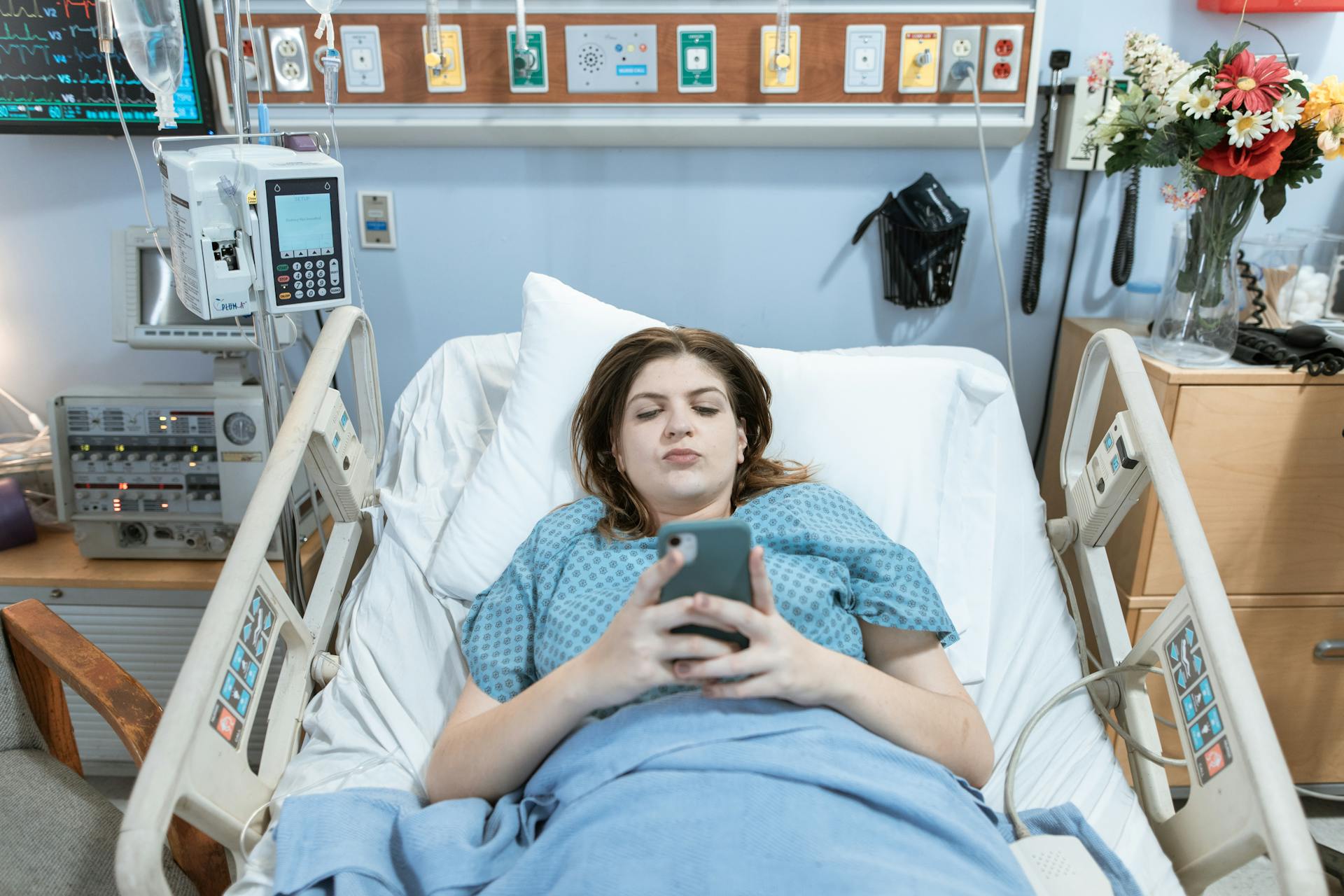 Une femme qui regarde son téléphone alors qu'elle est allongée sur un lit d'hôpital | Source : Pexels