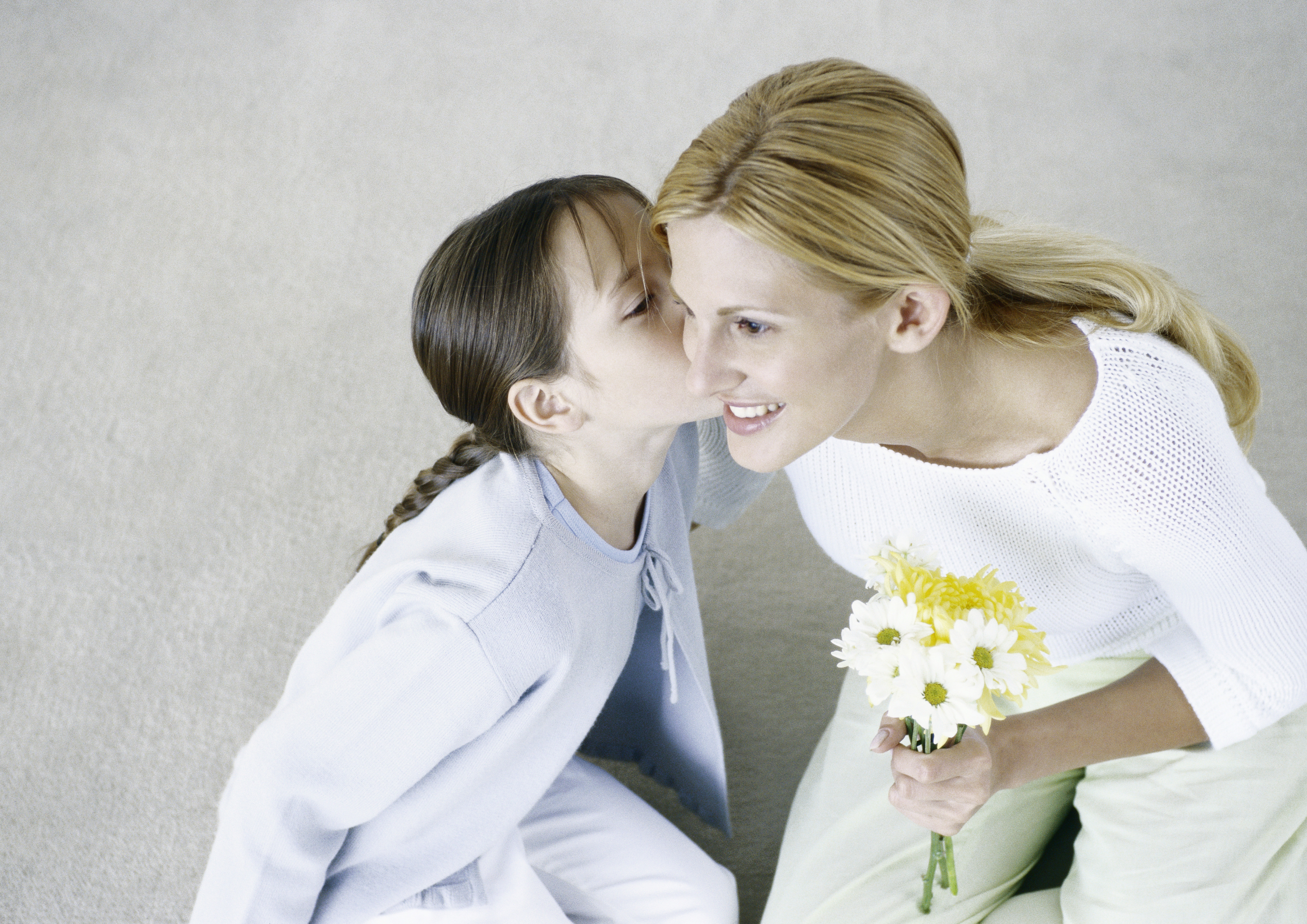 Femme tenant un bouquet de fleurs, fille l'embrassant sur la joue | Source : Getty Images