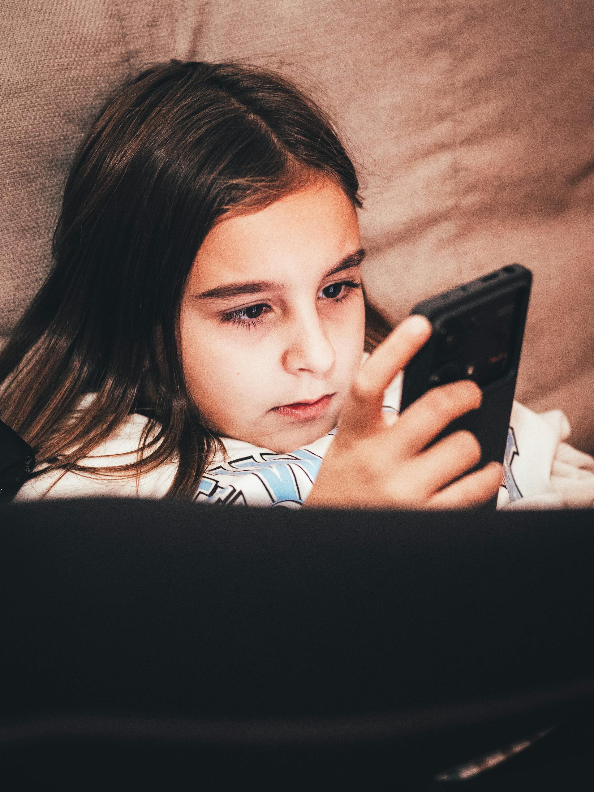 Une jeune adolescente fixant son téléphone portable | Source : Pexels