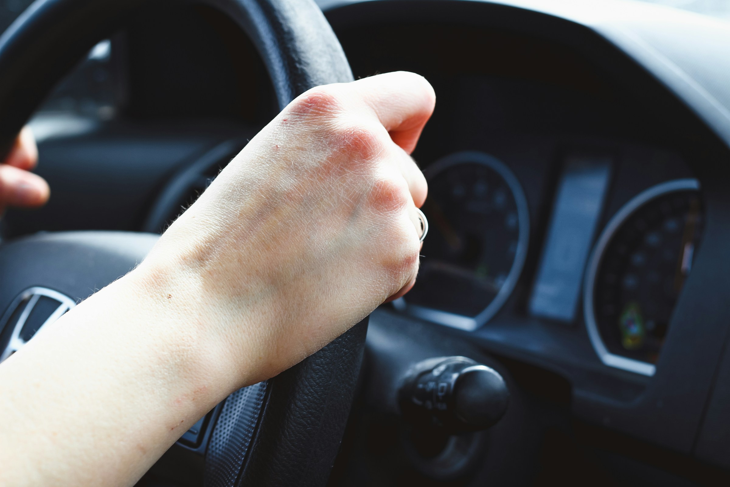 Un gros plan de mains agrippées au volant | Source : Unsplash