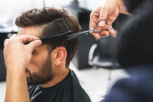 Coiffeur utilisant des ciseaux et un peigne. | Photo : Getty Images