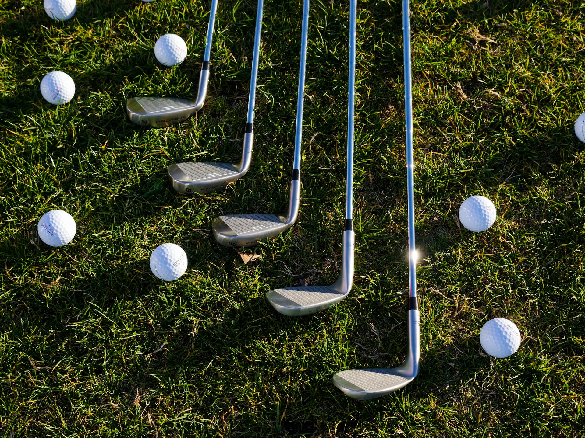Des balles et des clubs de golf posés sur l'herbe | Source : Pexels